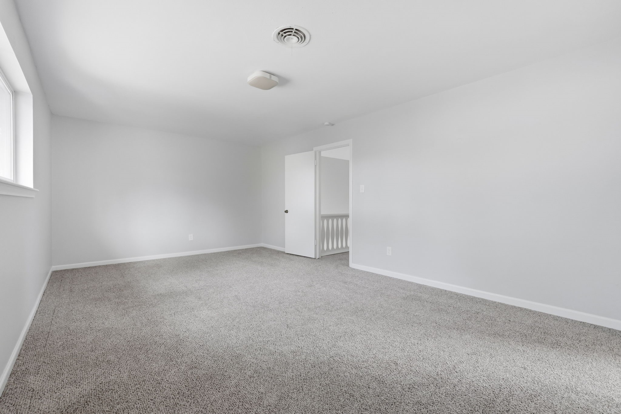 Spacious and bright room with neutral carpeting.