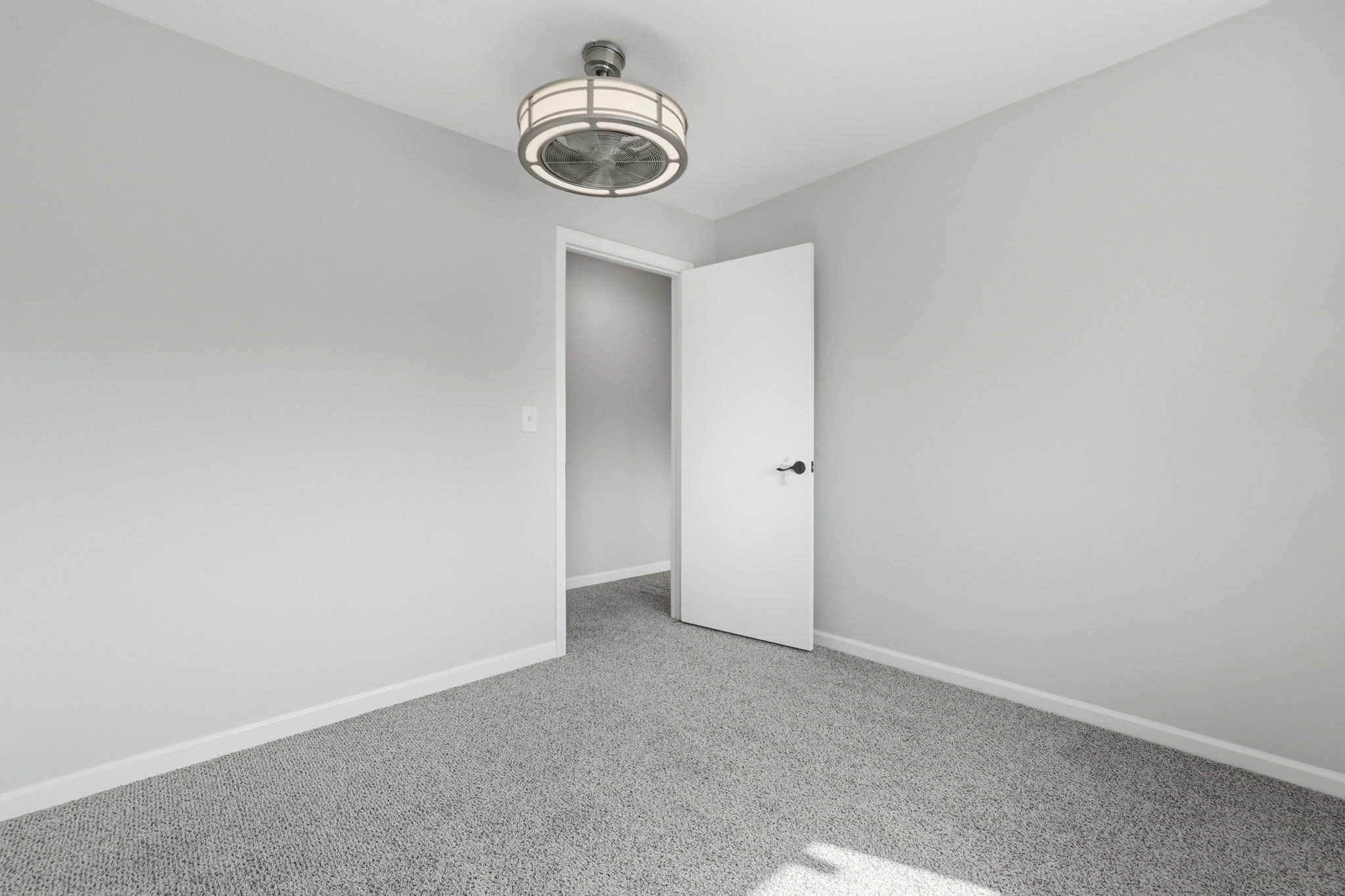 The room has fresh gray walls, plush carpeting, and a modern ceiling light.