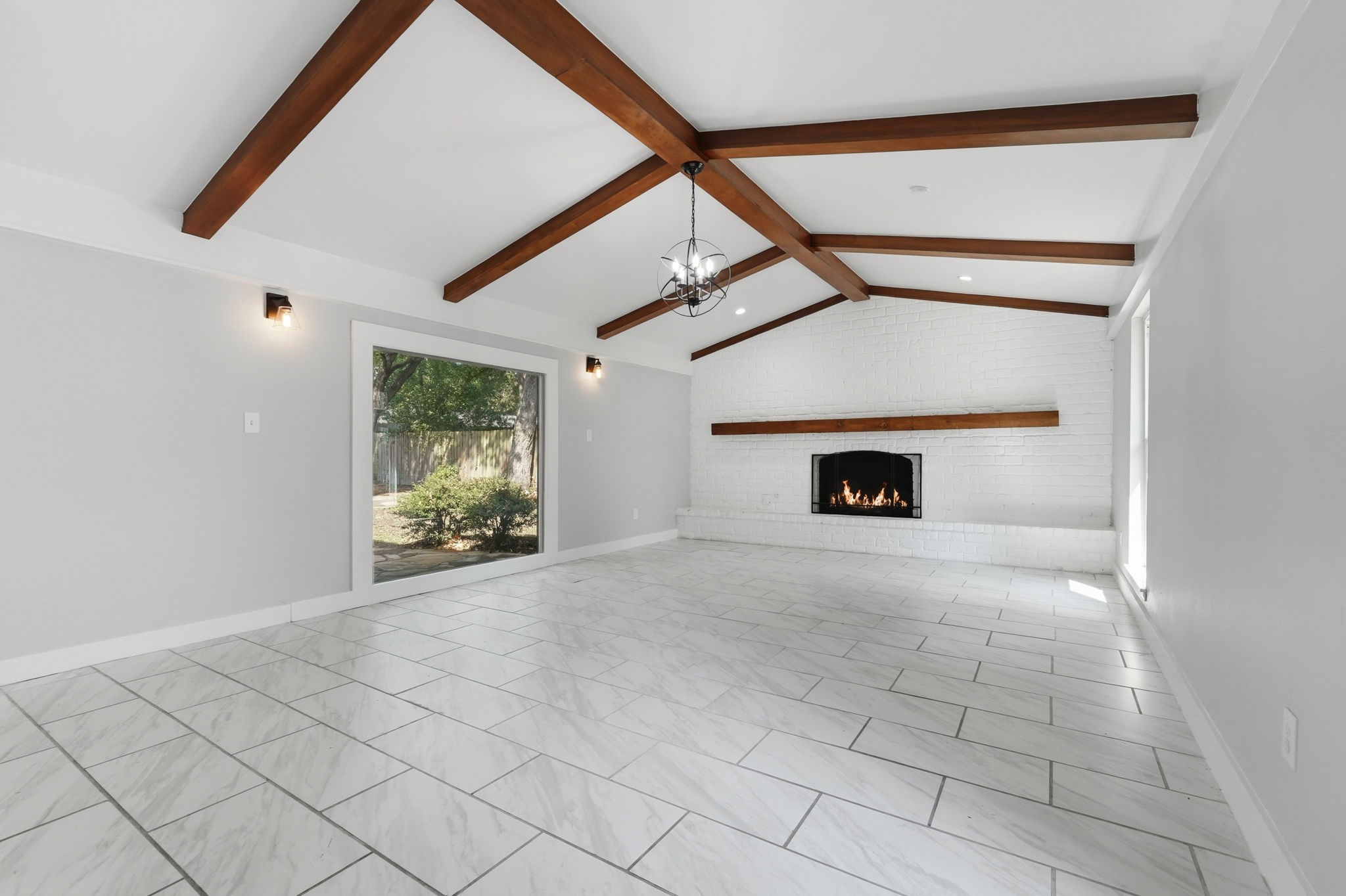 This large living room with an elegant wood-beamed ceiling and a cozy fireplace creates the perfect warm and inviting atmosphere.