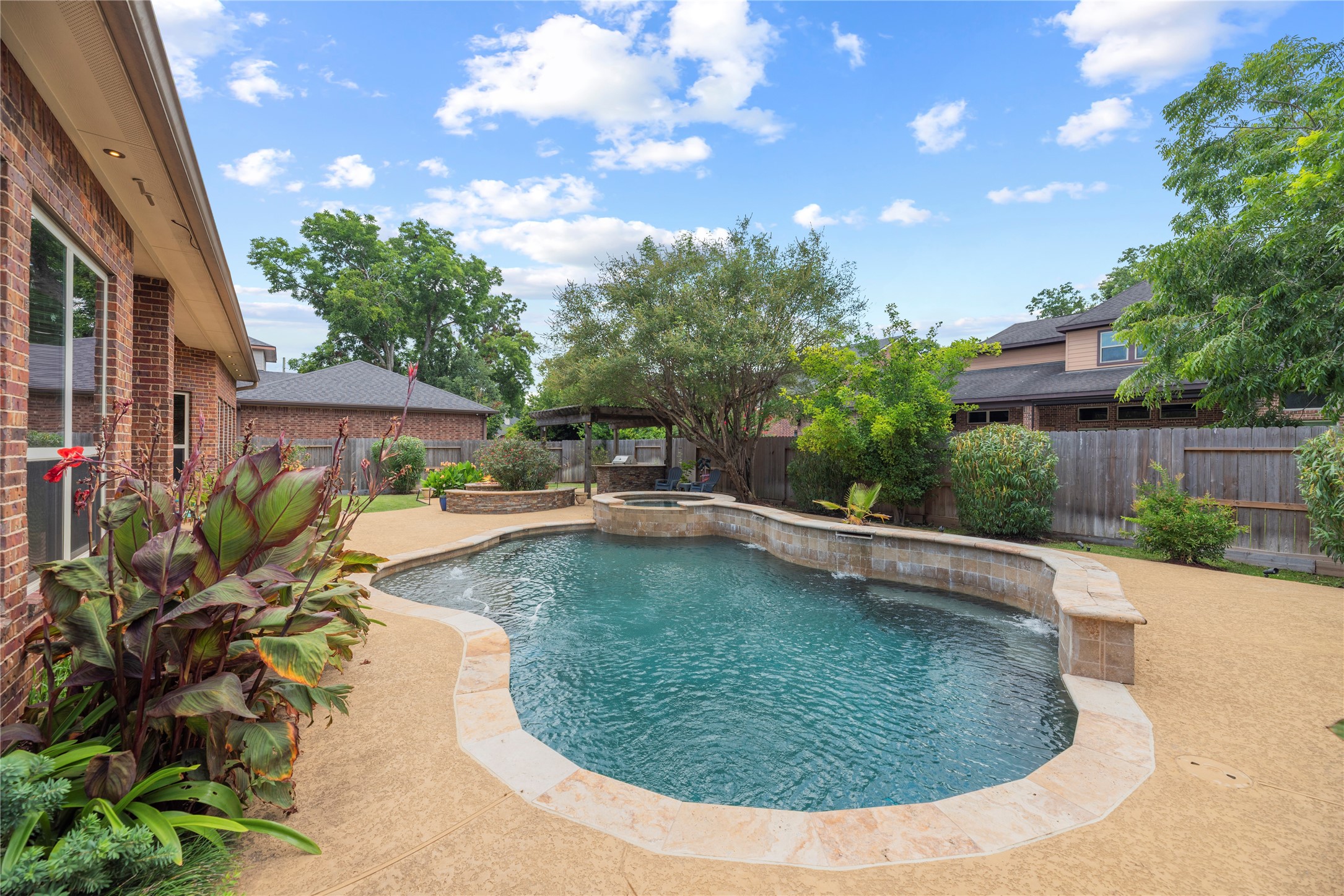 Sparkling pool and spa with water fall features - surrounded by lush landscaping.