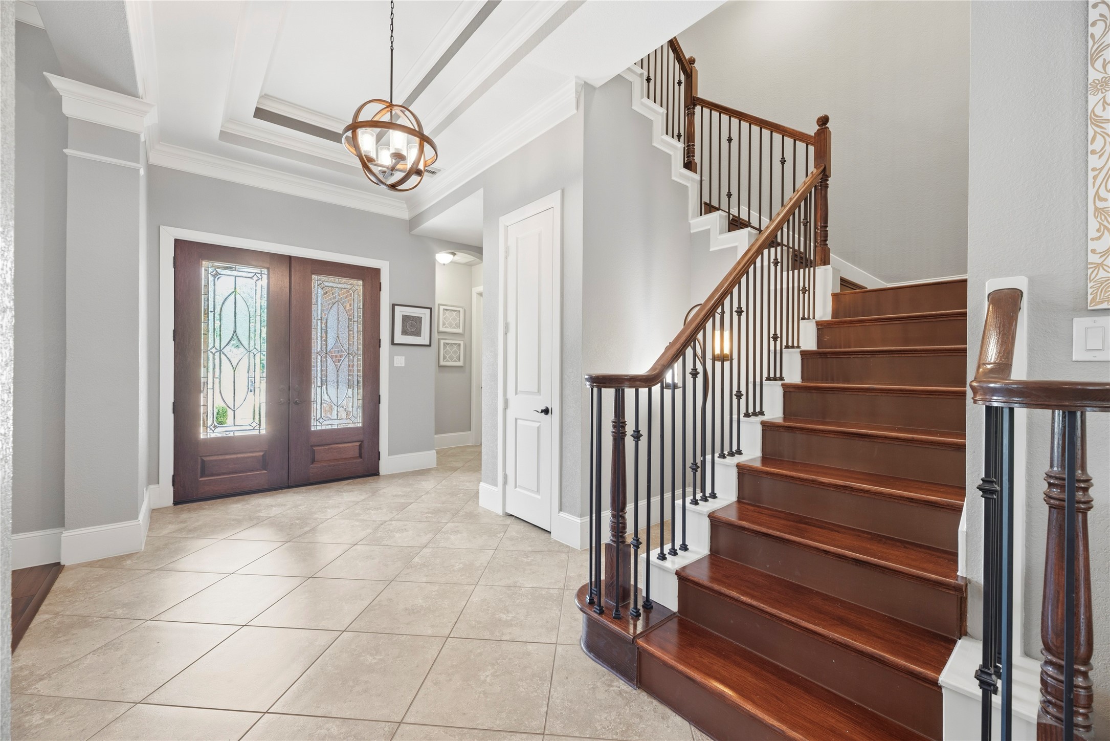 Wood double door entryway, coffered ceilings, and beautiful fixtures create a grand arrival experience.