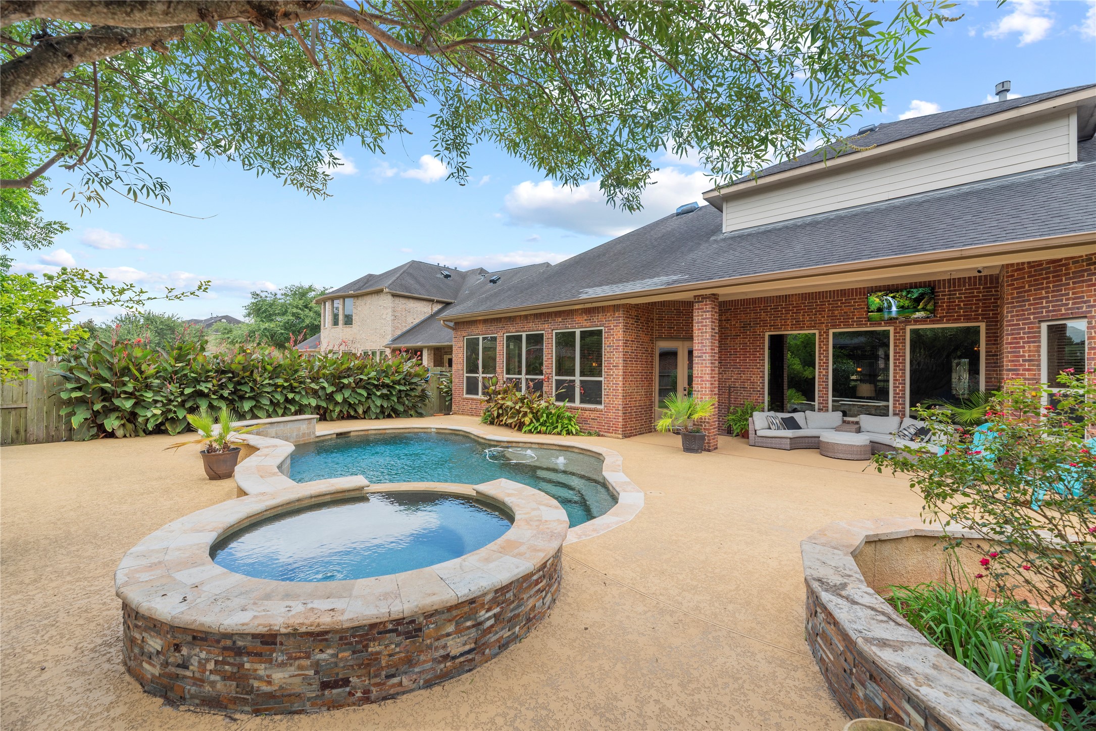 Sparkling pool and spa with water fall features - surrounded by lush landscaping.