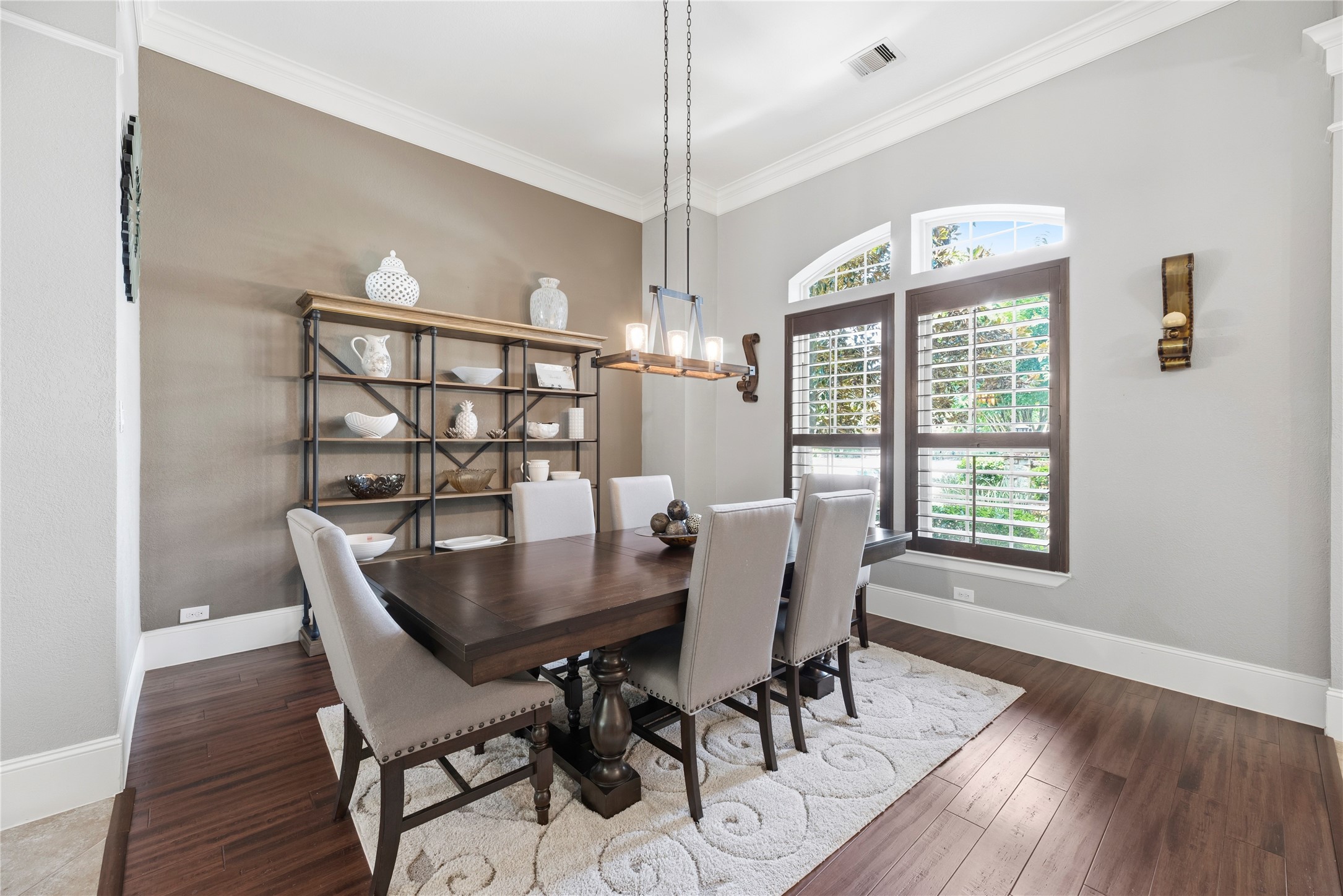 Host the next dinner party with confidence with this classy formal dining space. Featuring plantation shutters, crown molding, and an elegant light fixture.