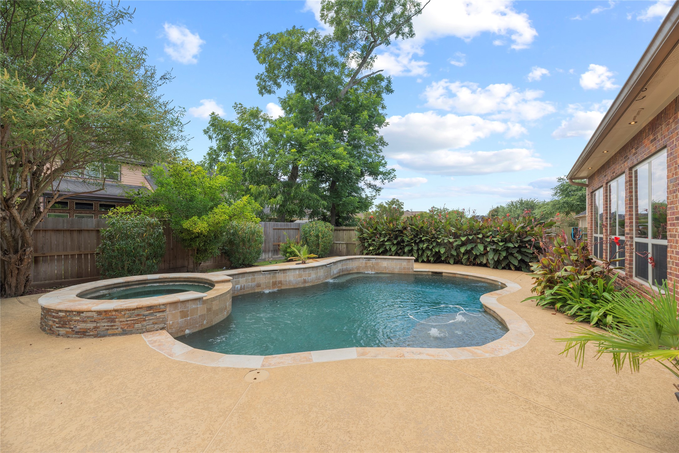 Sparkling pool and spa with water fall features - surrounded by lush landscaping.