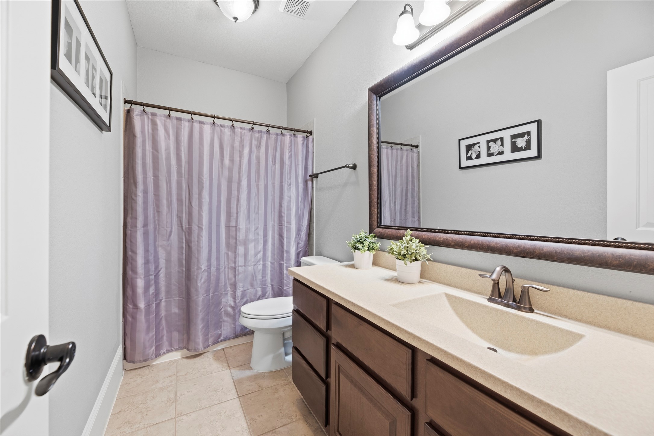 Well equipped secondary bathroom with a large vanity and shower/tub combo.