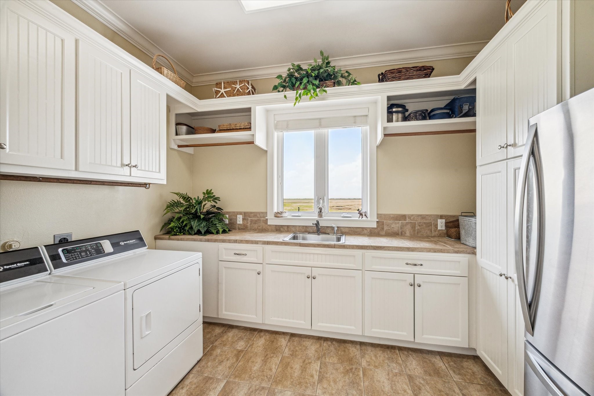 Generously sized laundry room featuring dedicated space for a second refrigerator or freezer