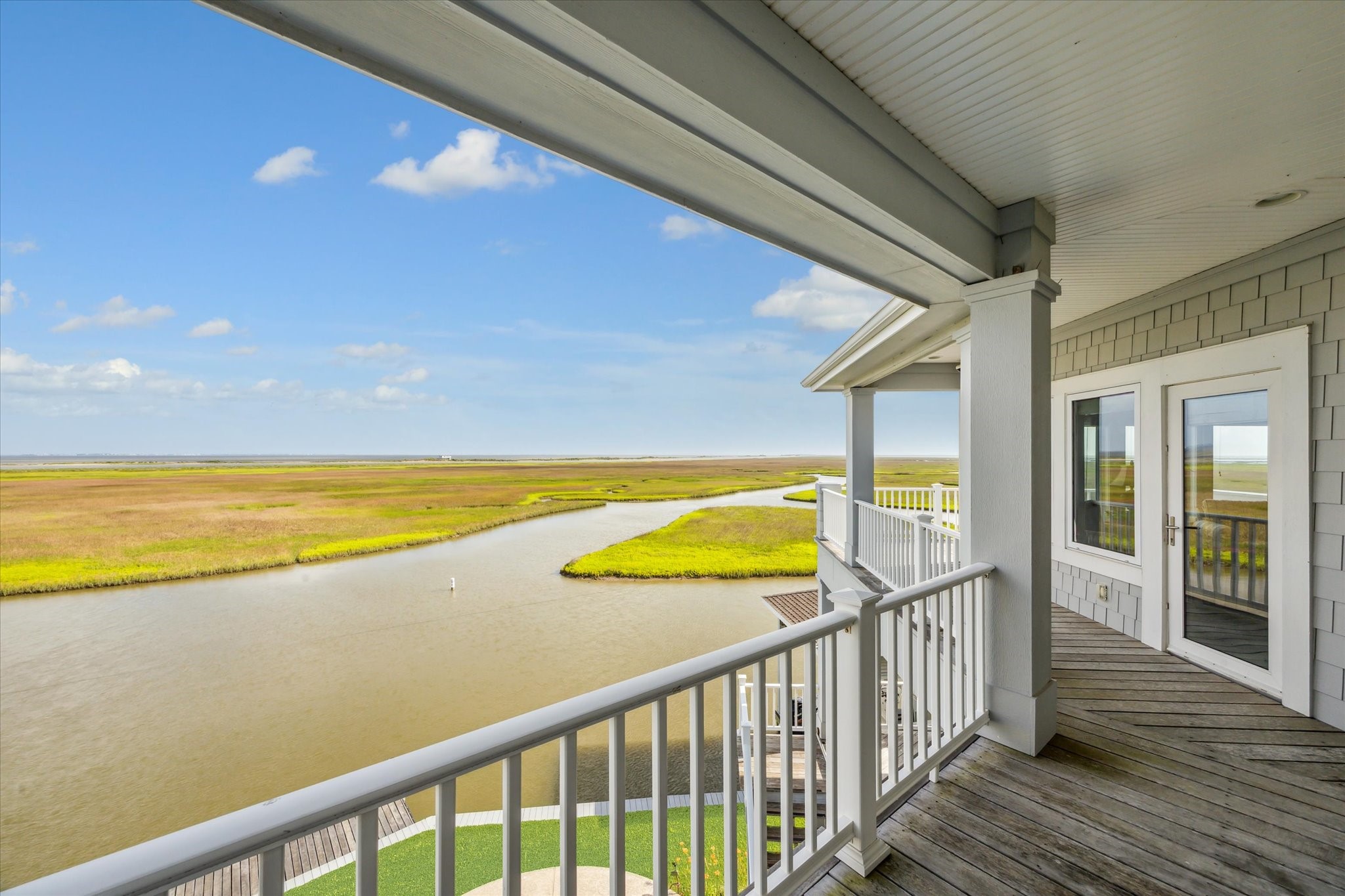 The top-level covered balcony offers panoramic, elevated views of the surrounding wetlands and West Galveston Bay