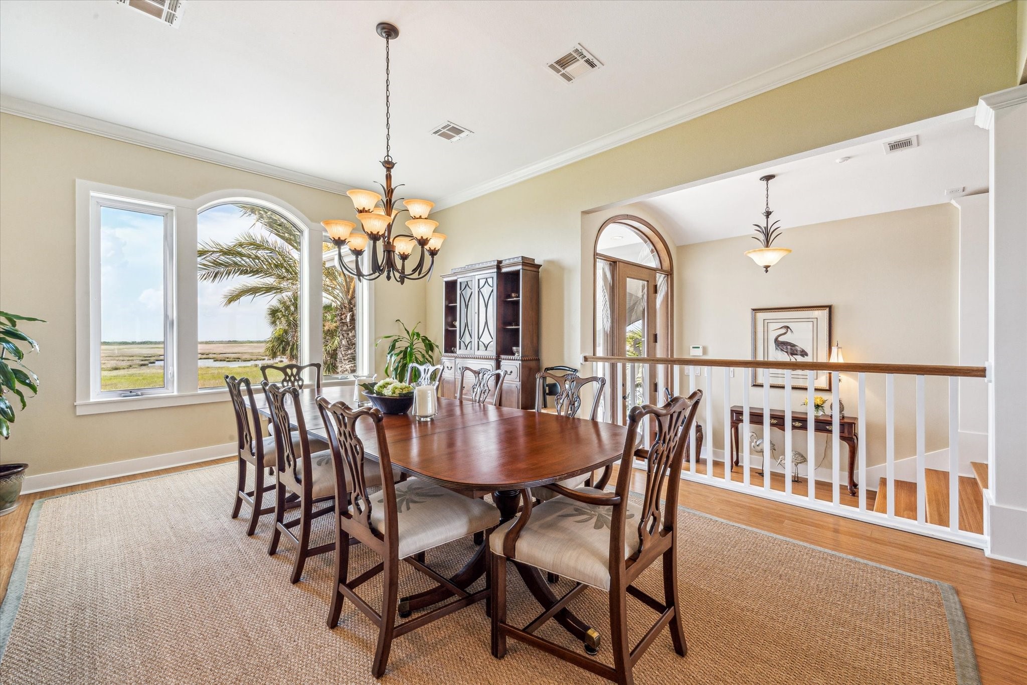 This stunning dining room offers sweeping views of the surrounding wetlands through a large picture window framed by elegant trim. A classic chandelier adds warmth and sophistication