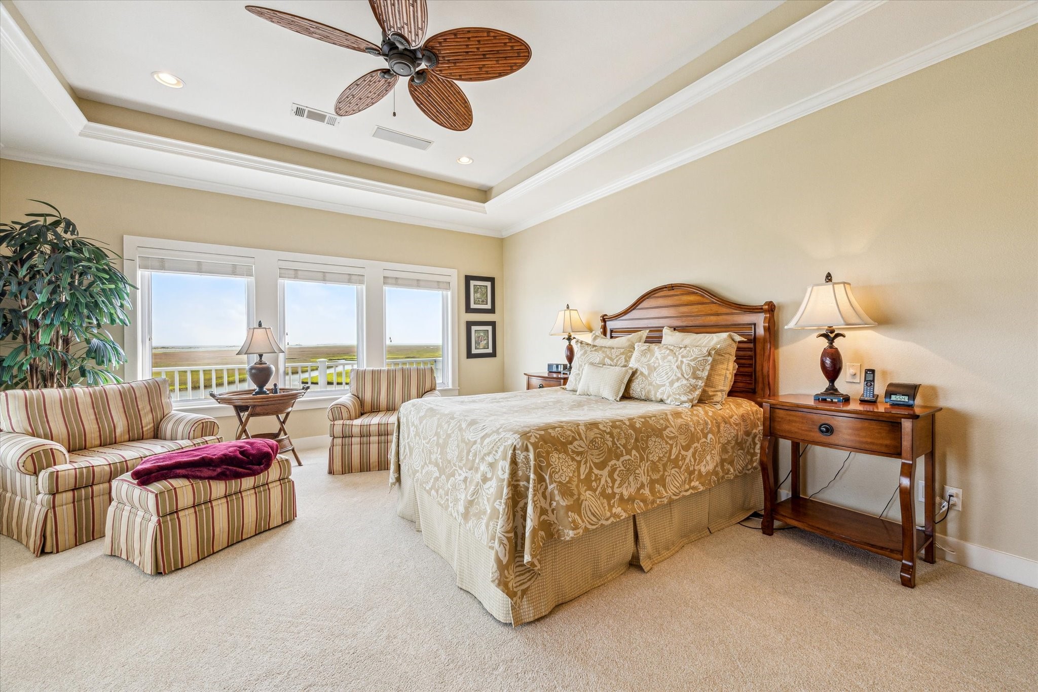 The primary bedroom is a spacious and serene retreat, designed to maximize the breathtaking views of the surrounding coastal landscape with access to upper level covered & open deck. A tray ceiling with recessed lighting and a tropical-style ceiling fan adds an elegant, airy feel to the room