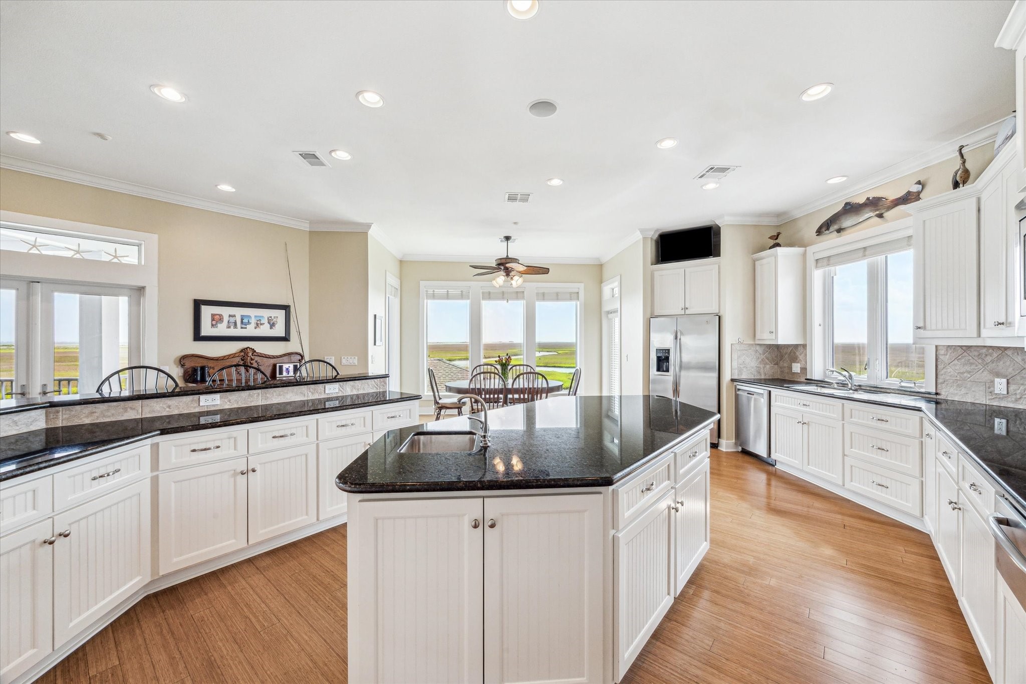 The kitchen features custom white beadboard cabinets that bring timeless design and coastal appeal, blending classic style with everyday functionality. Enjoy the ease of indoor/outdoor entertaining with direct access to a separte sunset deck from the kitchen