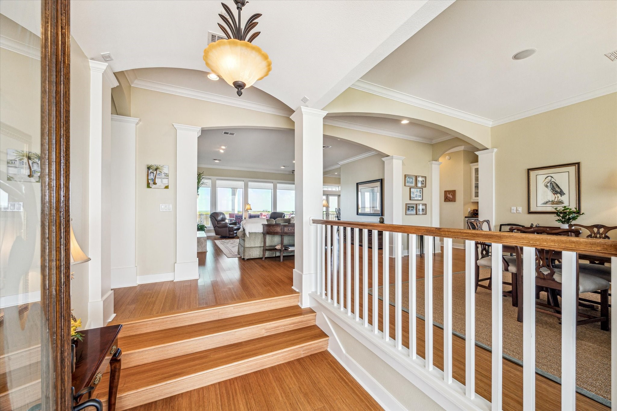 Upon entry, you're welcomed by rich bamboo flooring and staircase that leads into an open-concept layout. Elegant wood-columned archways define the space, creating a seamless flow from the foyer to the living and dining areas and beyond