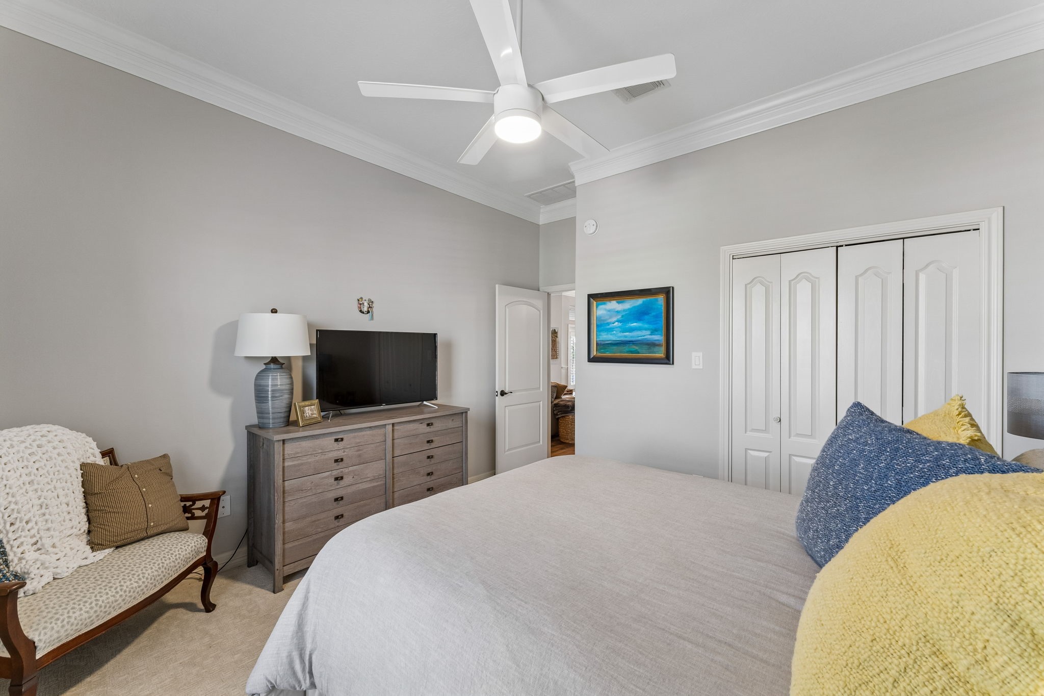 Generously sized bedroom features ample closet space and a clean, neutral palette. Crown molding and a modern ceiling fan add a polished finishing touch.