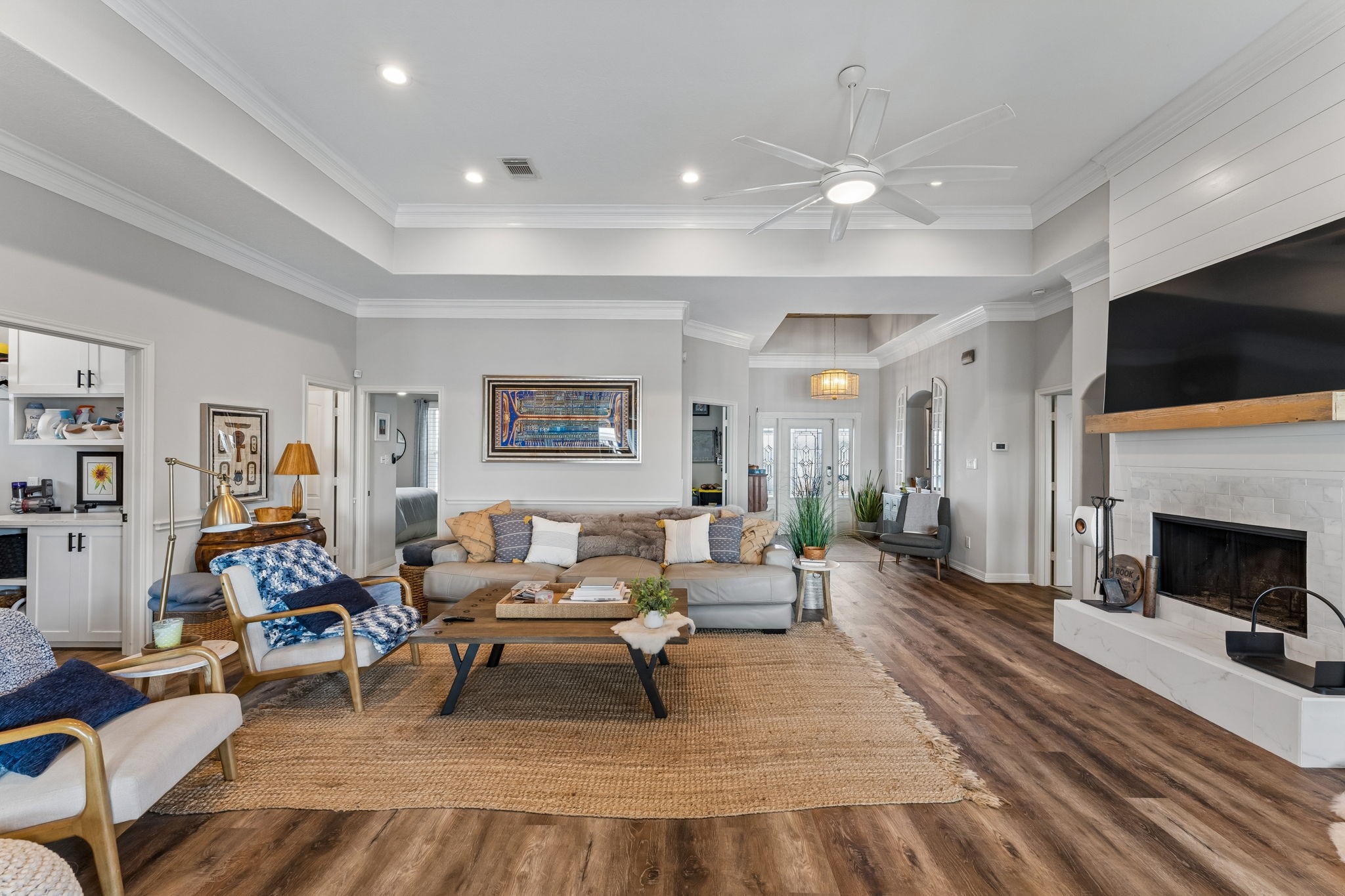 Expansive great room with soaring ceilings, warm wood flooring, and an inviting wood burning fireplace. The open layout creates an effortless flow for everyday living and entertaining.