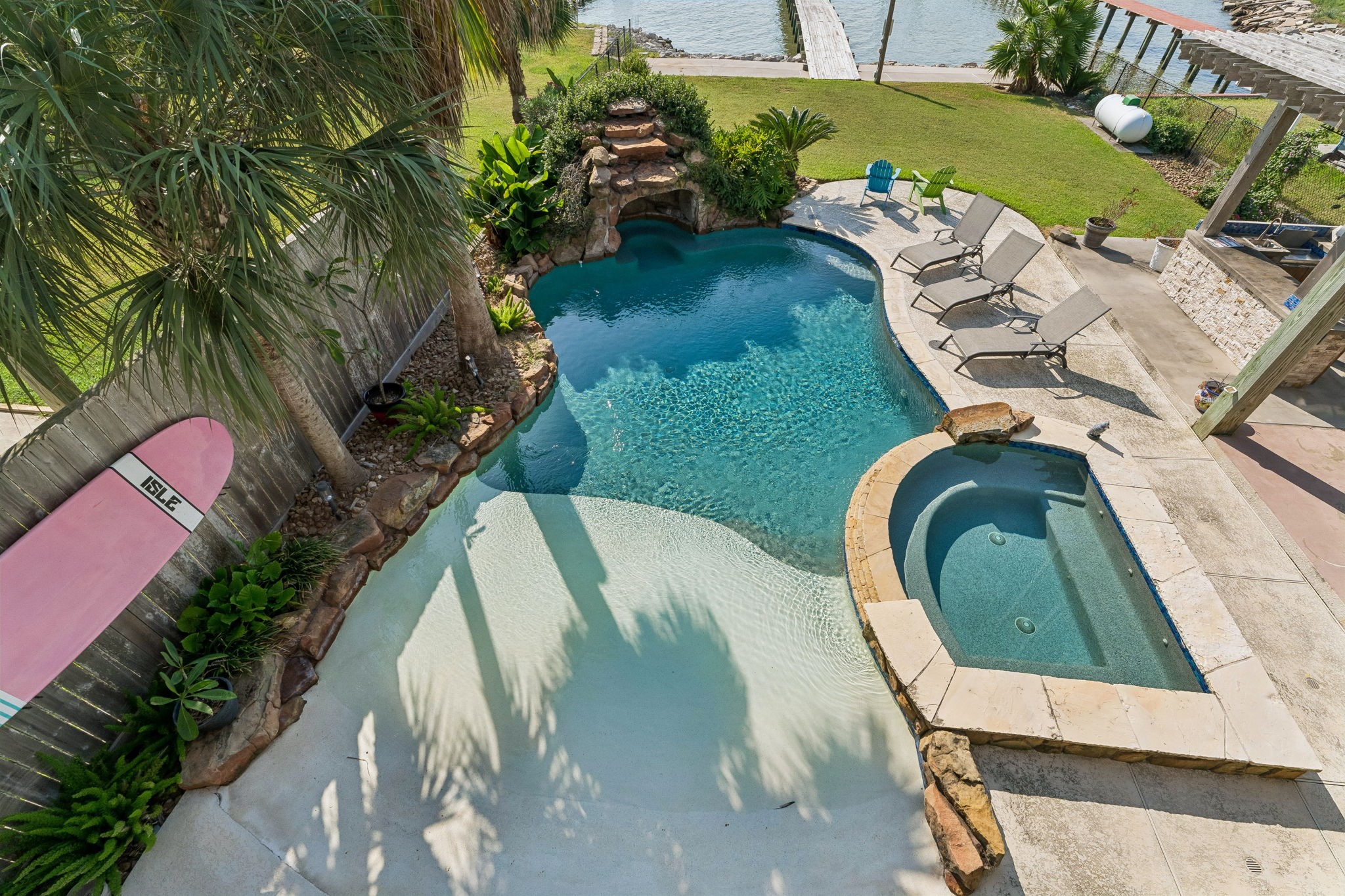 Resort style pool features a beach entry, built in hot tub, and cascading waterfall surrounded by tropical landscaping. Multiple lounging areas invite you to soak up the sun with Galveston Bay just beyond.