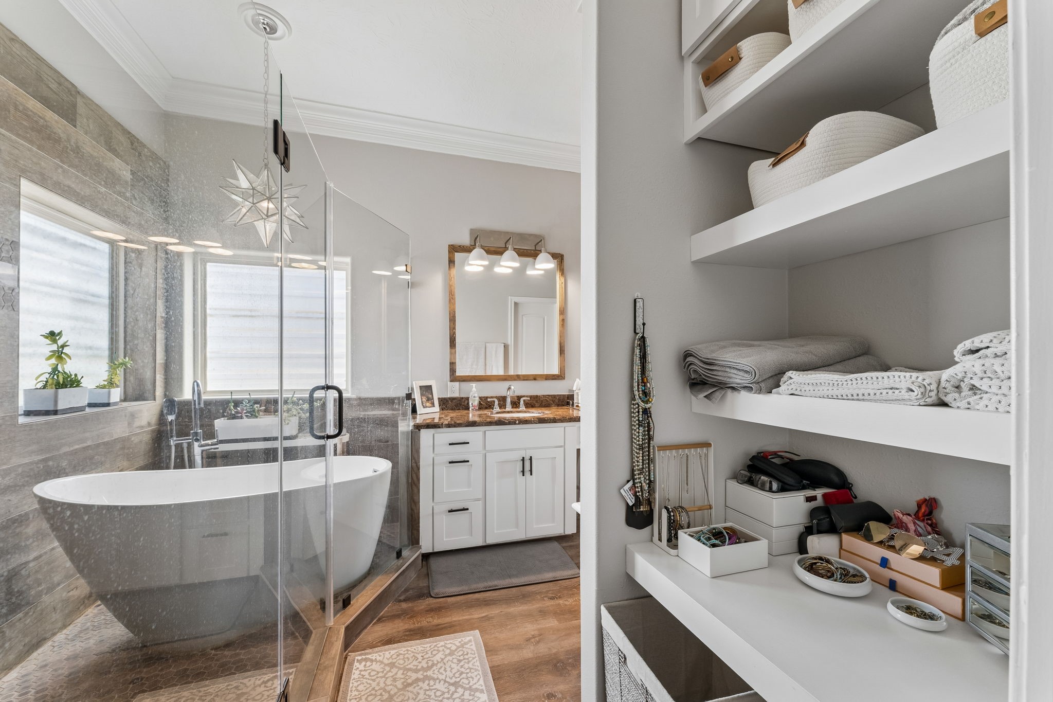 Thoughtfully designed primary ensuite includes built in open shelving for convenient storage and organization. The glass enclosed wet room pairs a freestanding soaking tub with a spacious shower for a true spa experience.