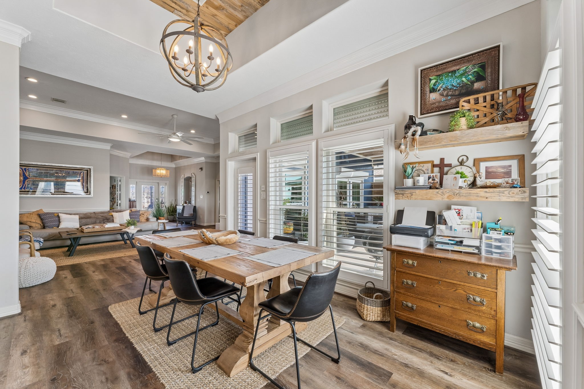 Bright dining area offers an inviting place to gather with seamless flow into the great room. Plantation shutters, floating wood shelves, and statement lighting add warmth and character.