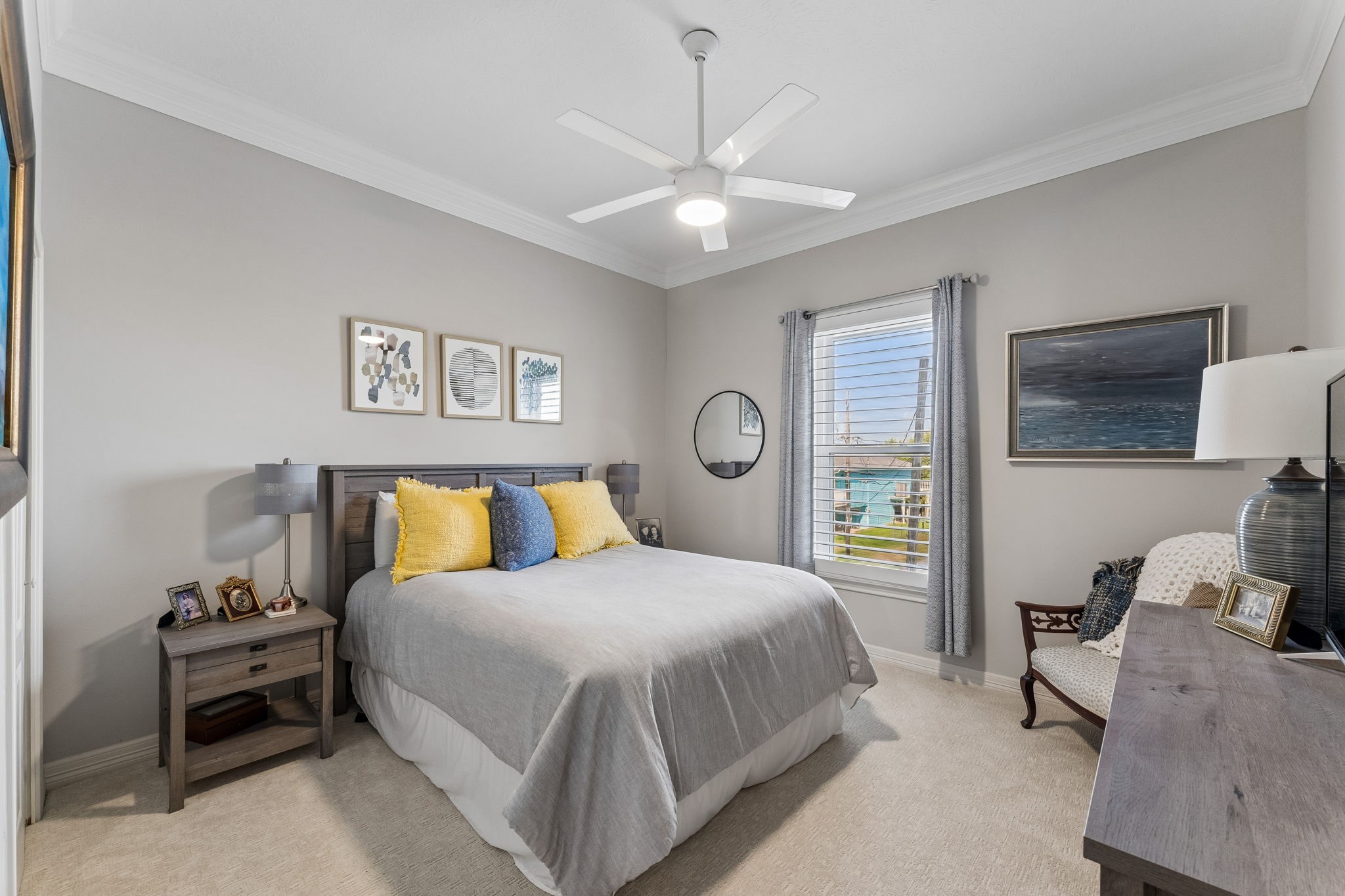 Comfortable bedroom offers a calm, inviting atmosphere with soft natural light and neutral finishes. A ceiling fan and generous proportions create an easy, relaxing space.