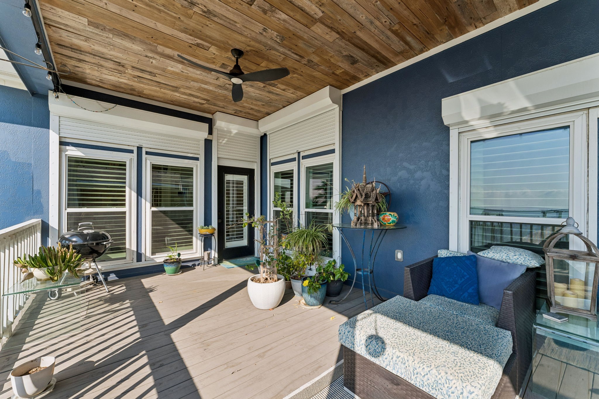 Covered balcony creates a relaxing outdoor lounge with shade, ceiling fan, and comfortable seating. Enjoy refreshing bay breezes and water views just beyond the railing.