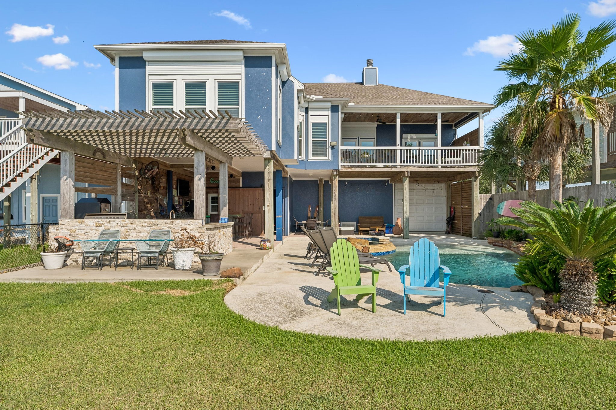 Expansive backyard brings together a sparkling pool, covered entertaining areas, and a lush lawn for the ultimate outdoor lifestyle. Multiple seating areas offer plenty of space to relax and enjoy the coastal setting.