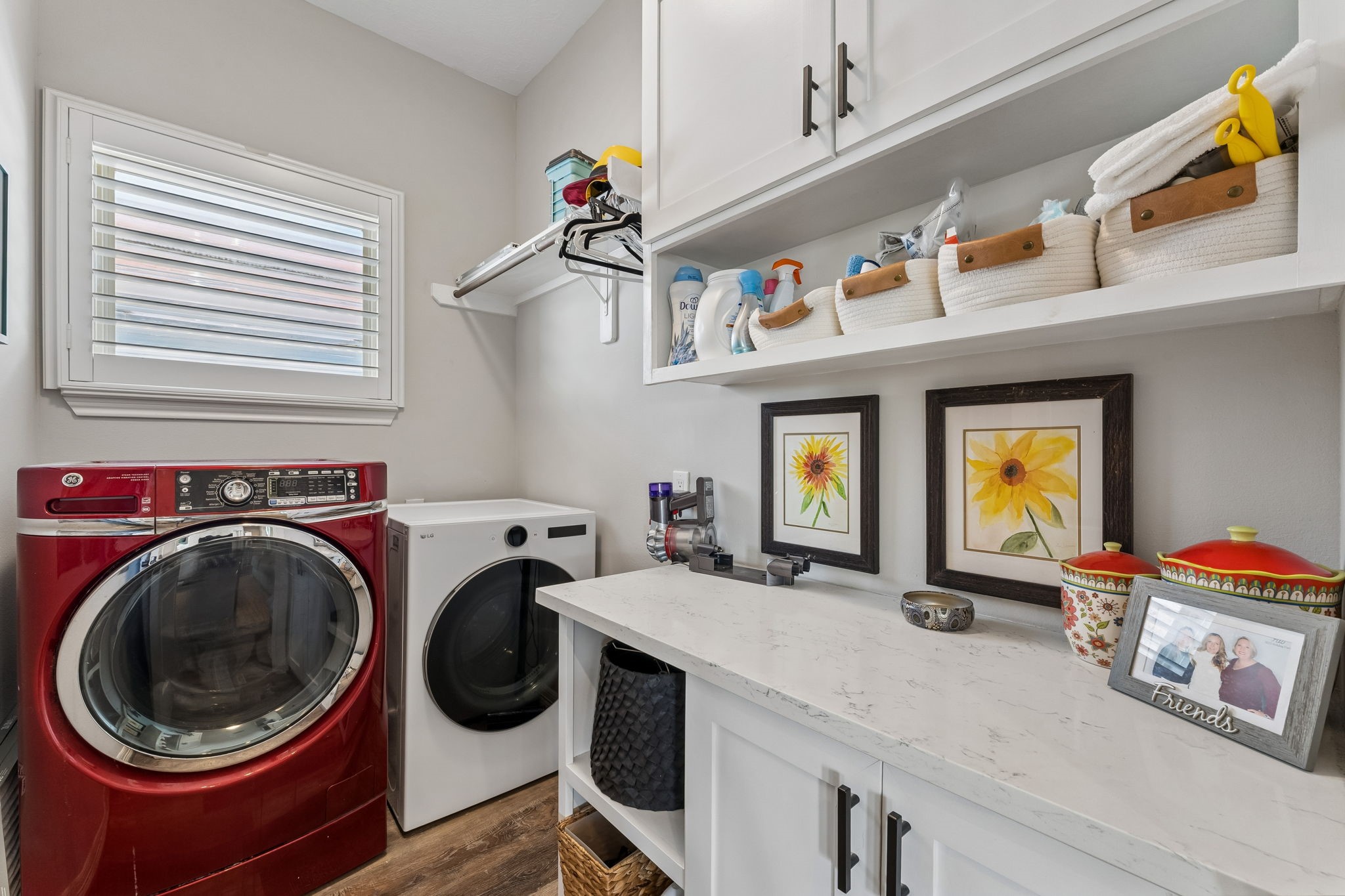 Dedicated laundry room offers generous cabinetry, counter space, and open shelving for added organization. A window brings natural light into this functional everyday space.
