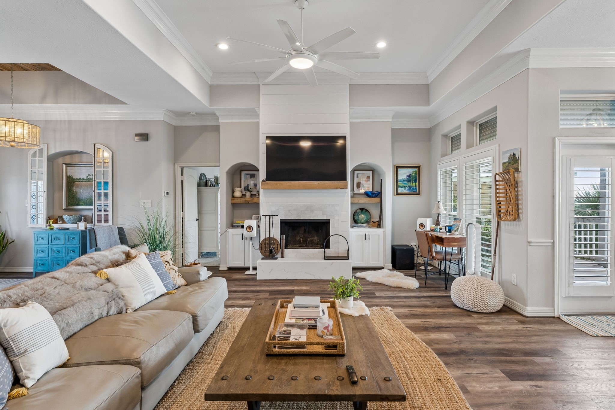 Inviting living area centered around a wood burning fireplace with custom built ins and a statement media wall. Abundant natural light and direct outdoor access enhance the bright, open feel.
