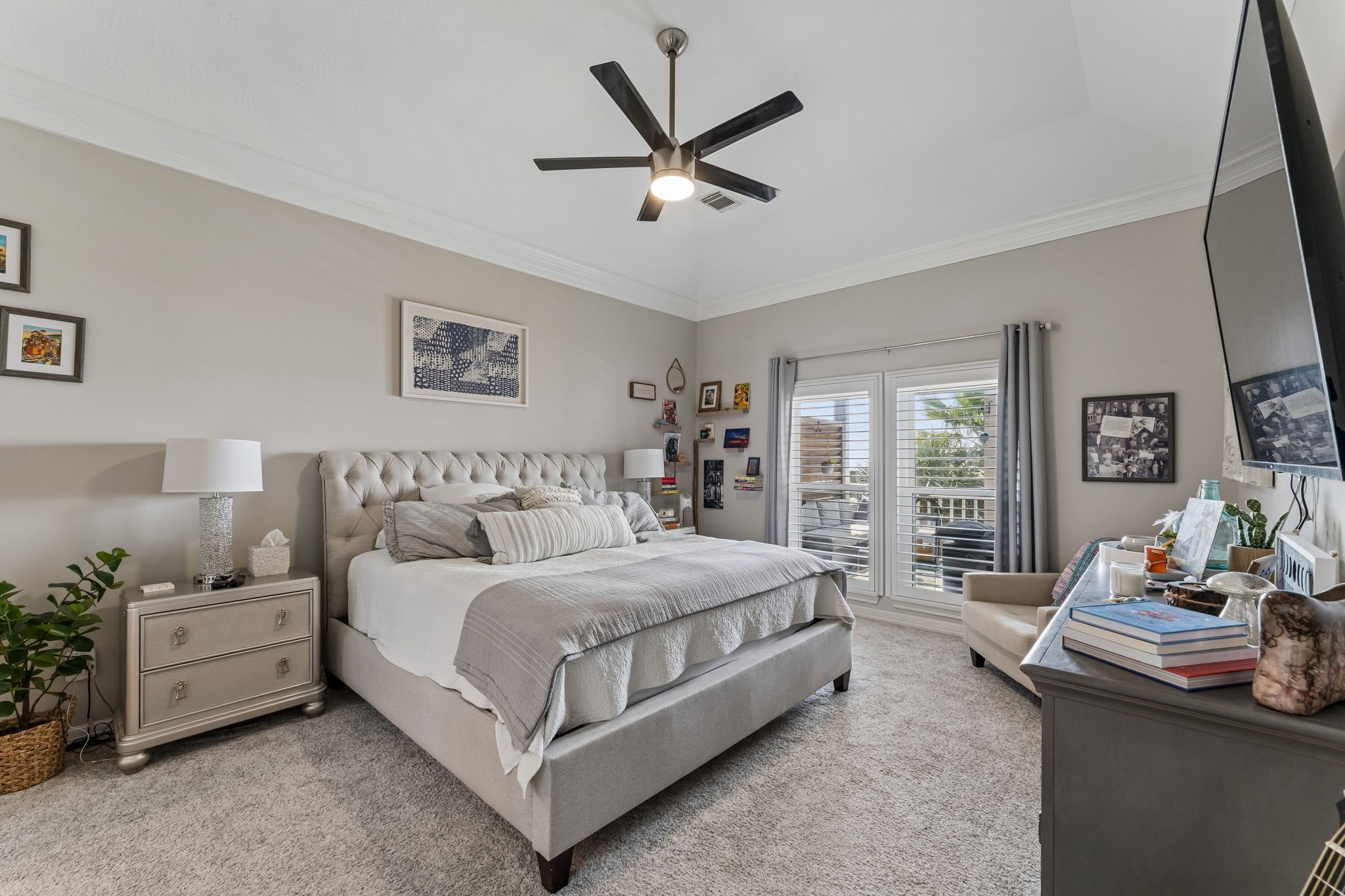 Spacious primary suite offers a serene setting with high ceilings and plush finishes. French doors open to a private balcony, extending the living space outdoors.