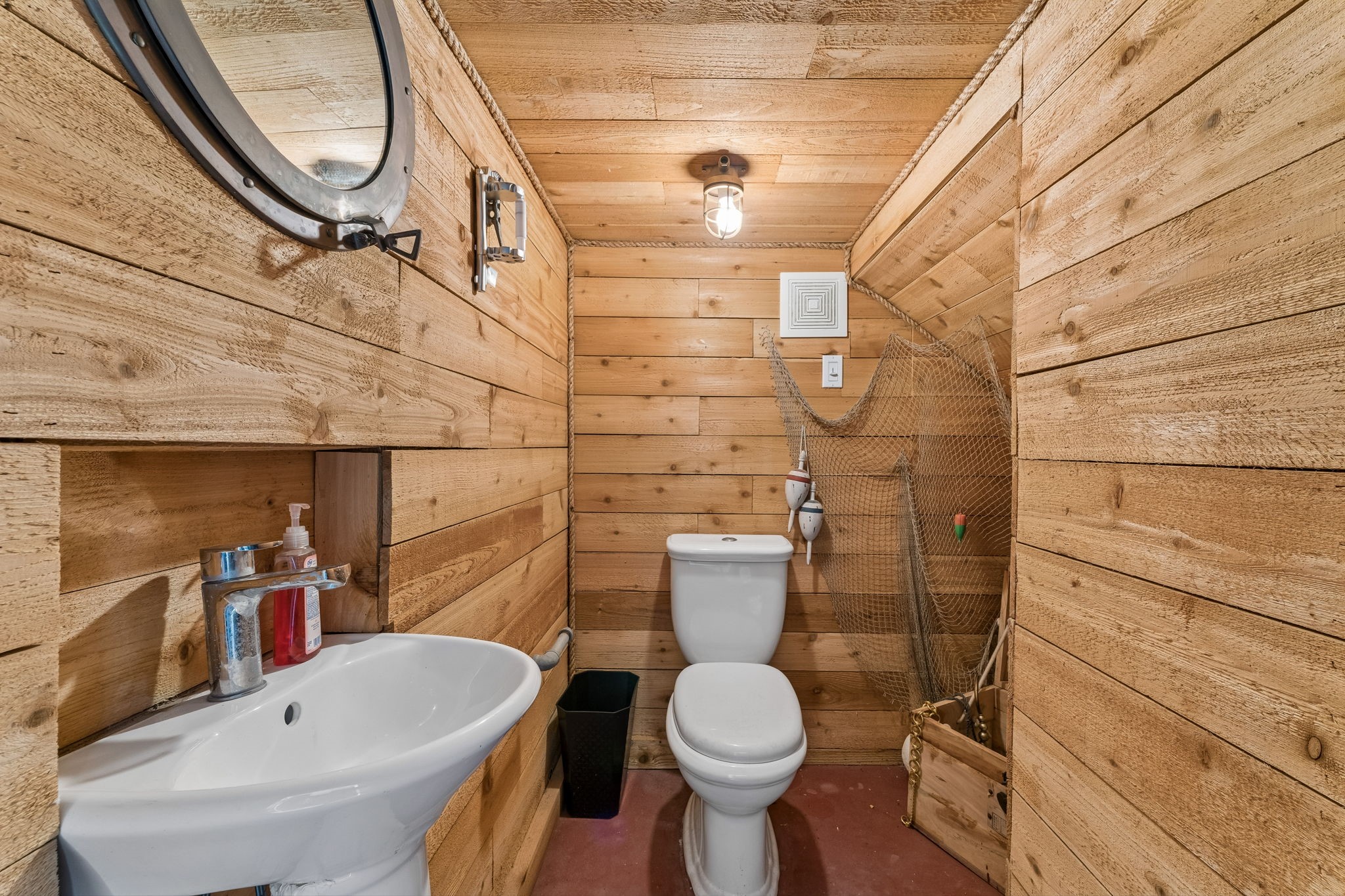 Convenient powder room features warm wood plank walls for a distinctive coastal touch. A compact design adds functionality for guests and outdoor entertaining.