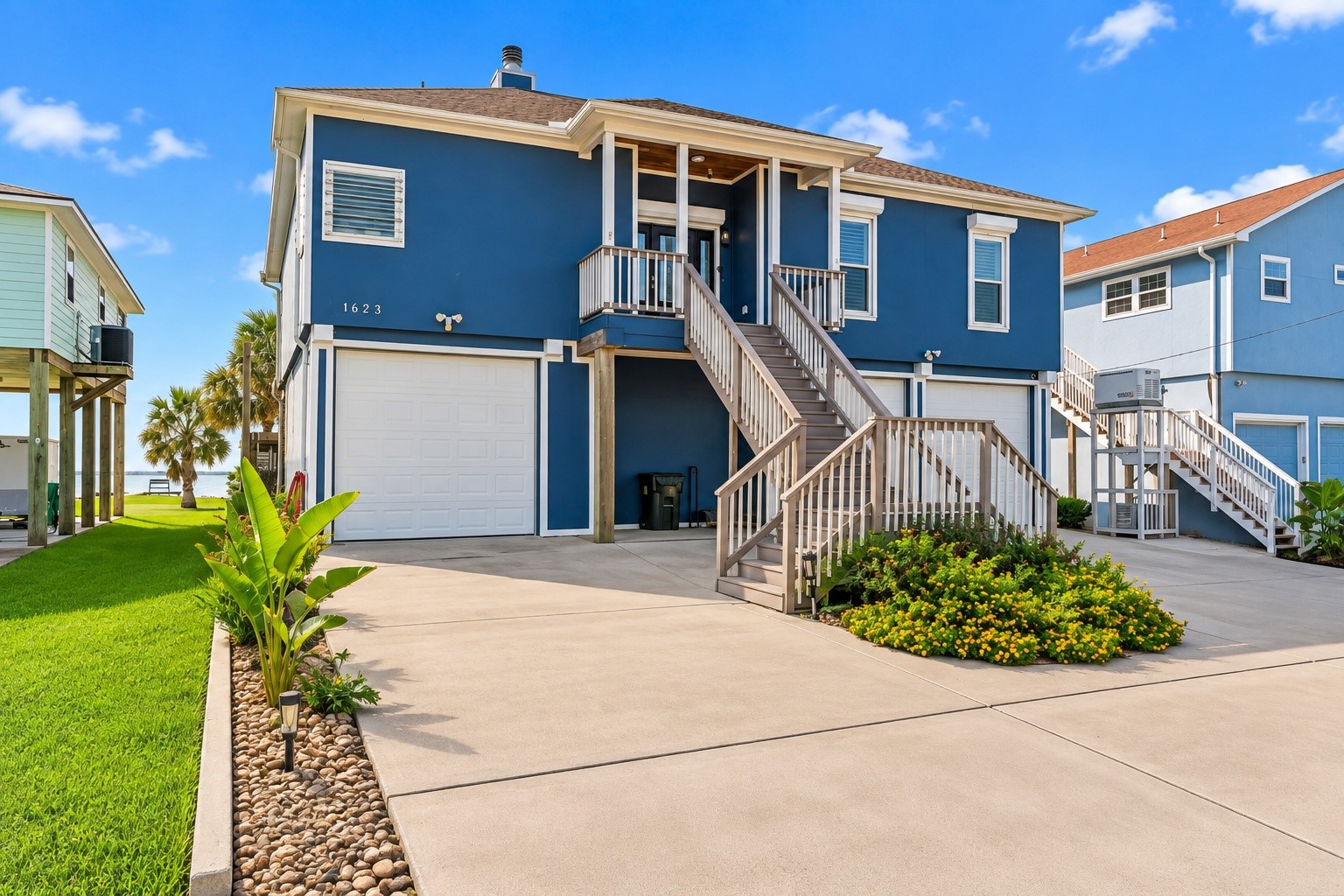 Wide driveway provides generous parking and easy access to the garage beneath the elevated home. Manicured landscaping and coastal architecture create a welcoming curb appeal. Wide driveway provides generous parking and easy access to the garage beneath the elevated home. Manicured landscaping and coastal architecture create a welcoming curb appeal.