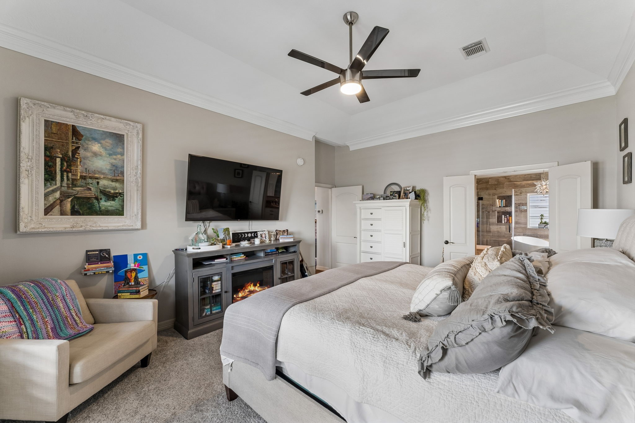 Another view of the primary suite highlights its generous proportions and comfortable sitting area. A wide doorway provides direct access to the beautifully appointed primary ensuite.