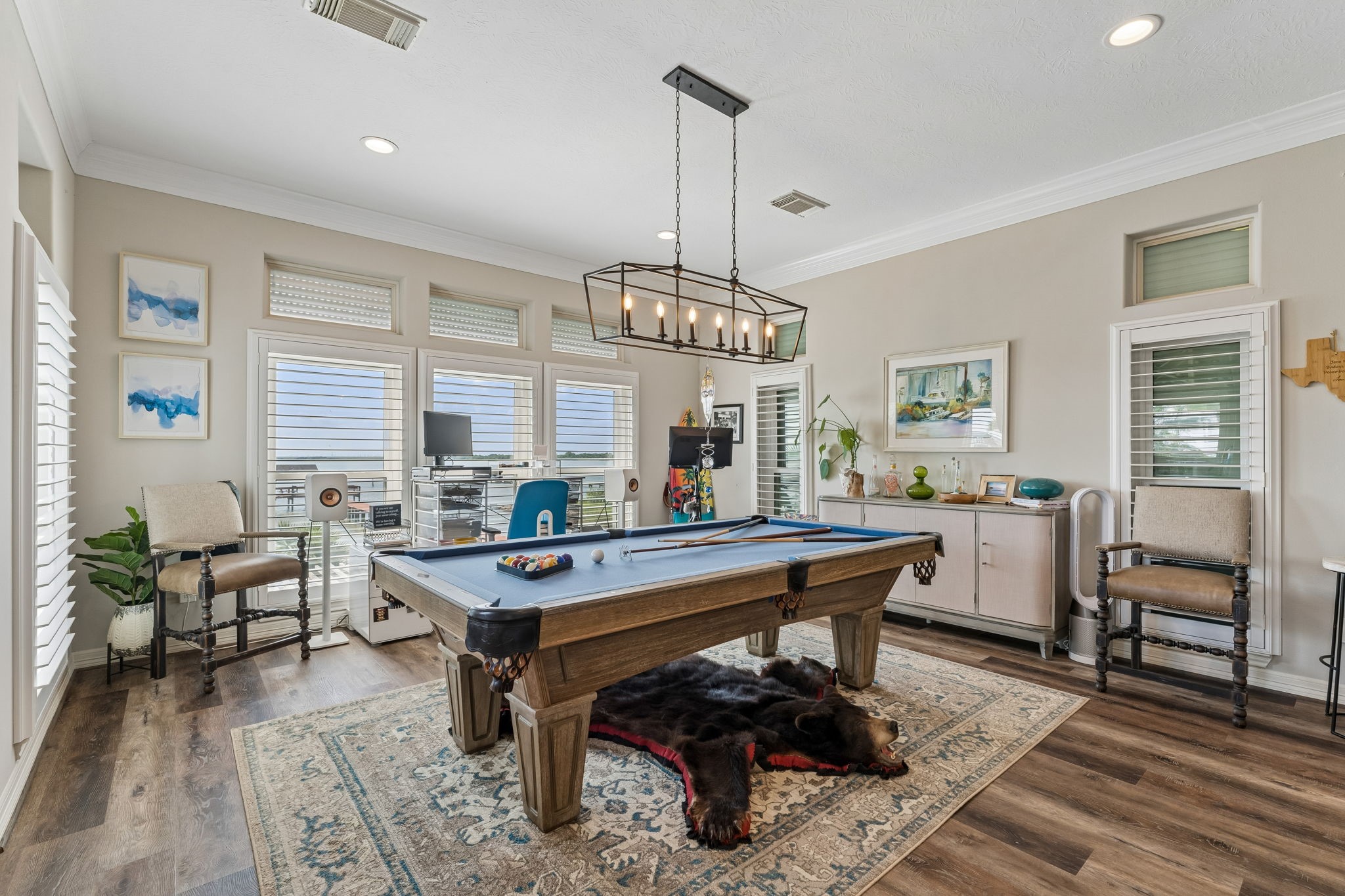 Versatile game room offers plenty of space for a pool table, lounge seating, and entertainment. Walls of windows keep the space bright while capturing views of the waterfront surroundings.