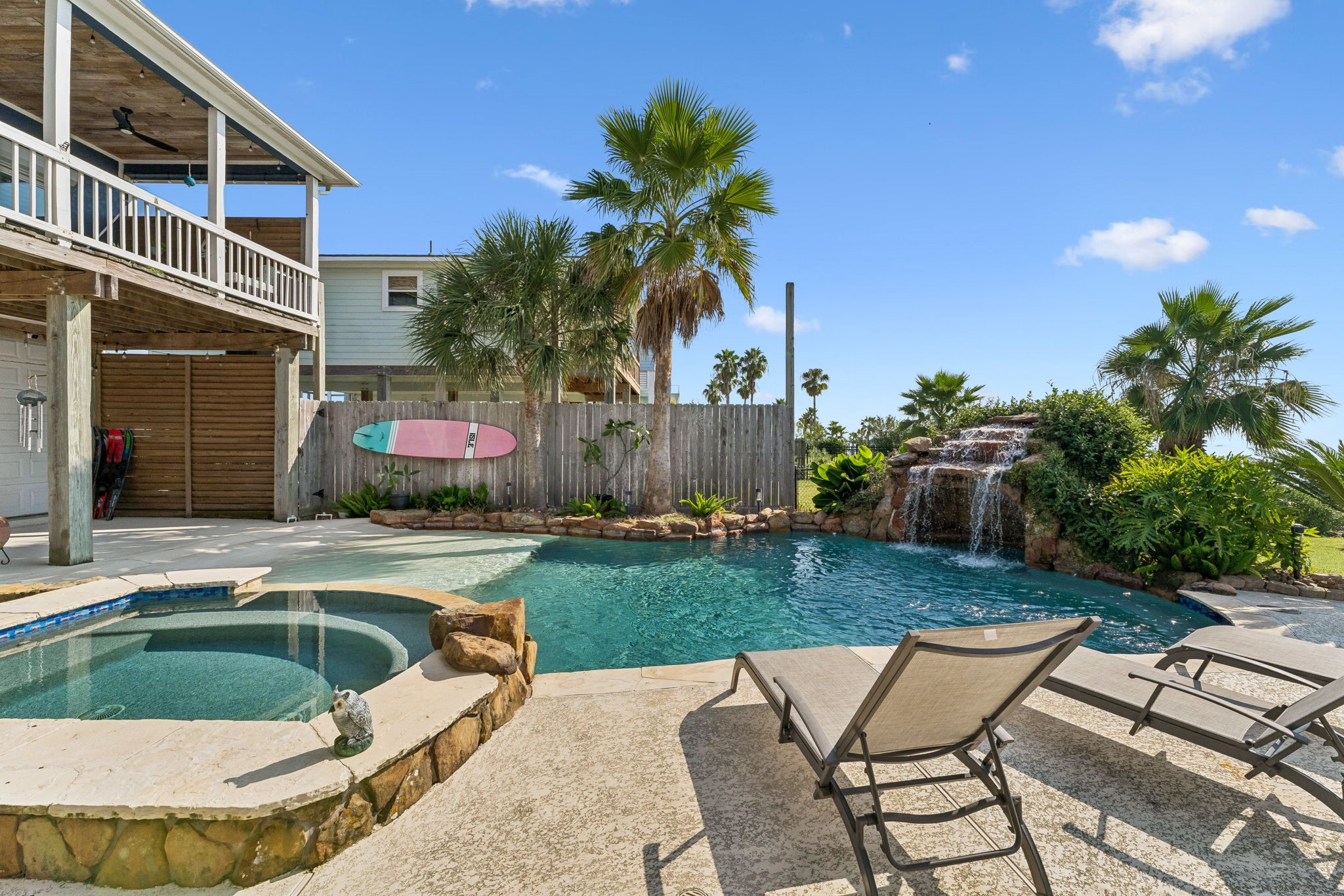 Sun drenched pool deck offers plenty of space for lounging beside the water. Tropical landscaping and the cascading waterfall create a private coastal escape.