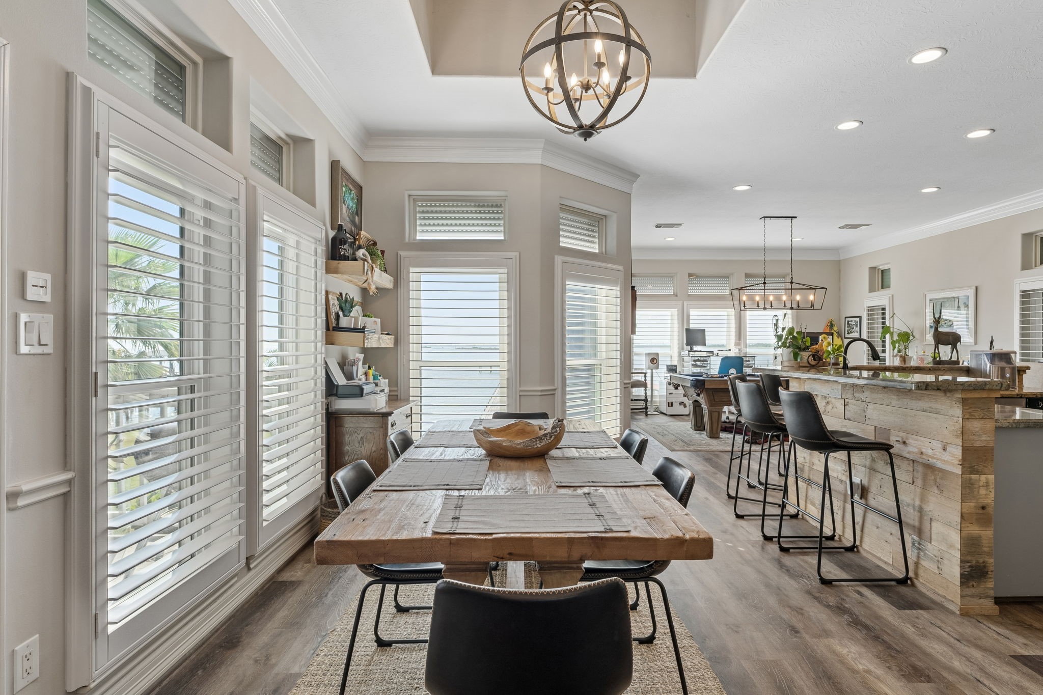Light filled dining area flows seamlessly into the kitchen, creating an inviting space for gathering and entertaining. Expansive windows and plantation shutters bring in abundant natural light.