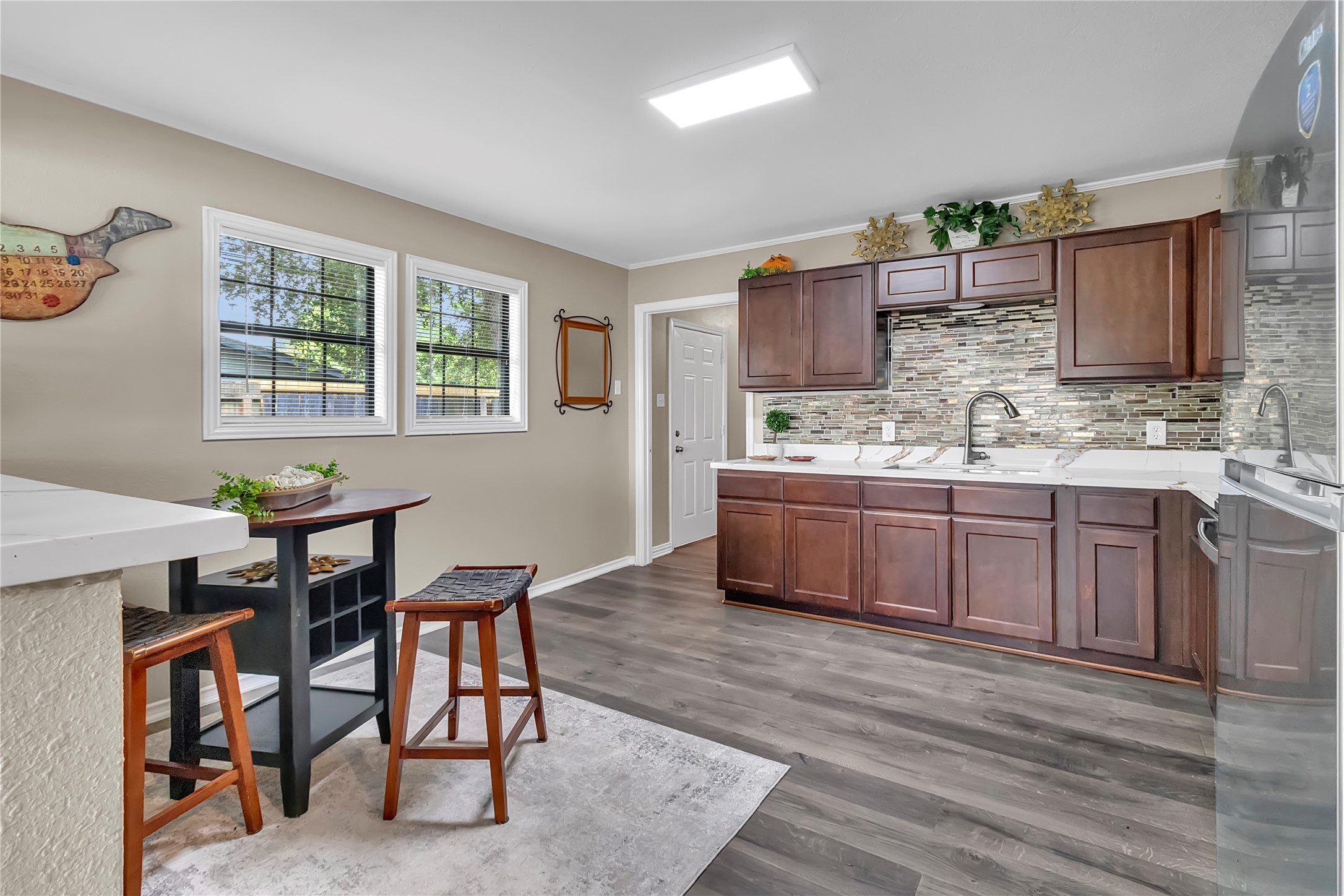 Updated kitchen with rich cabinetry, decorative backsplash, stainless appliances, and space for casual dining.