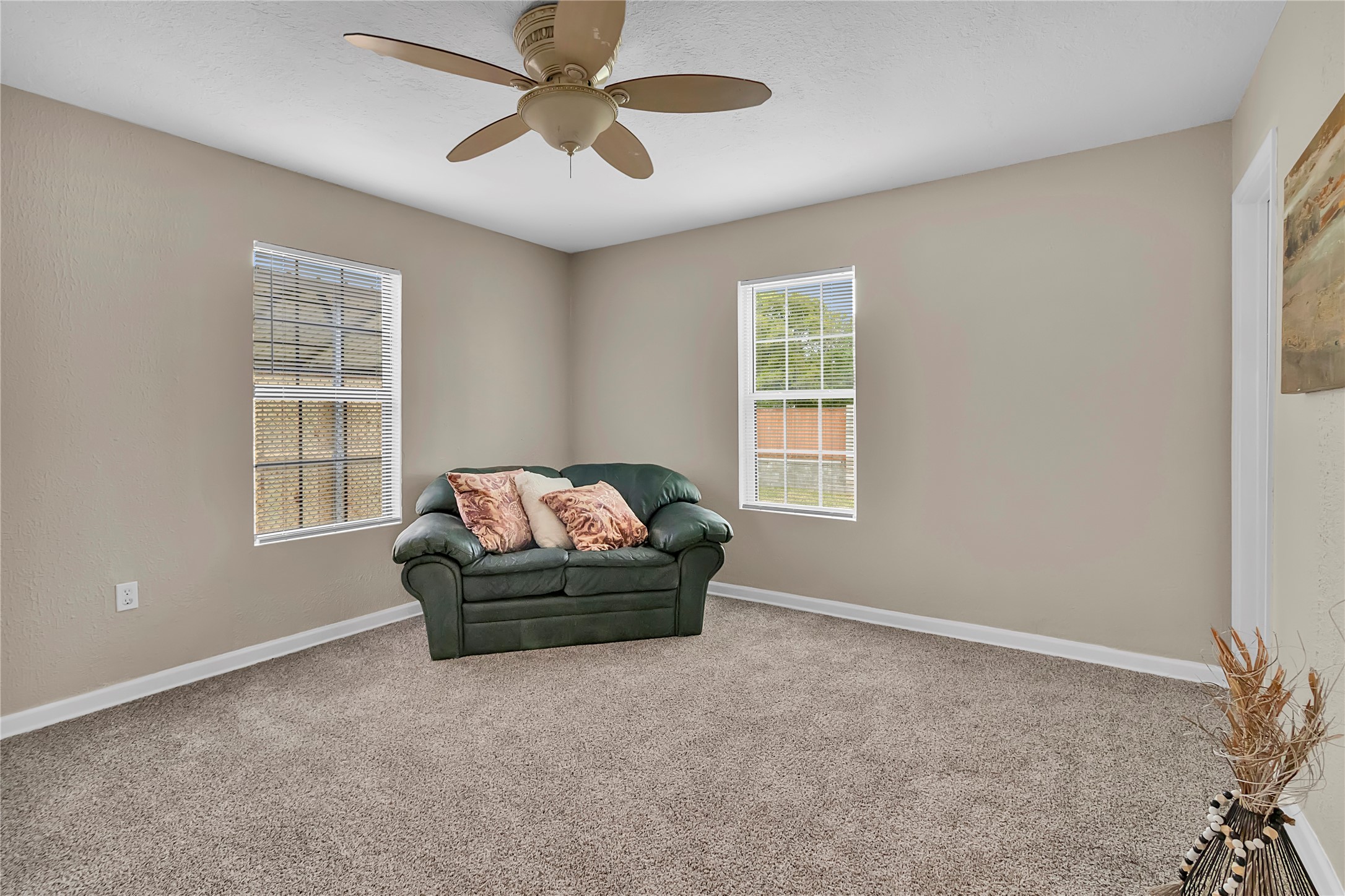 Bright and spacious 4th bedroom with fresh carpet, ceiling fan, and windows overlooking the property.
