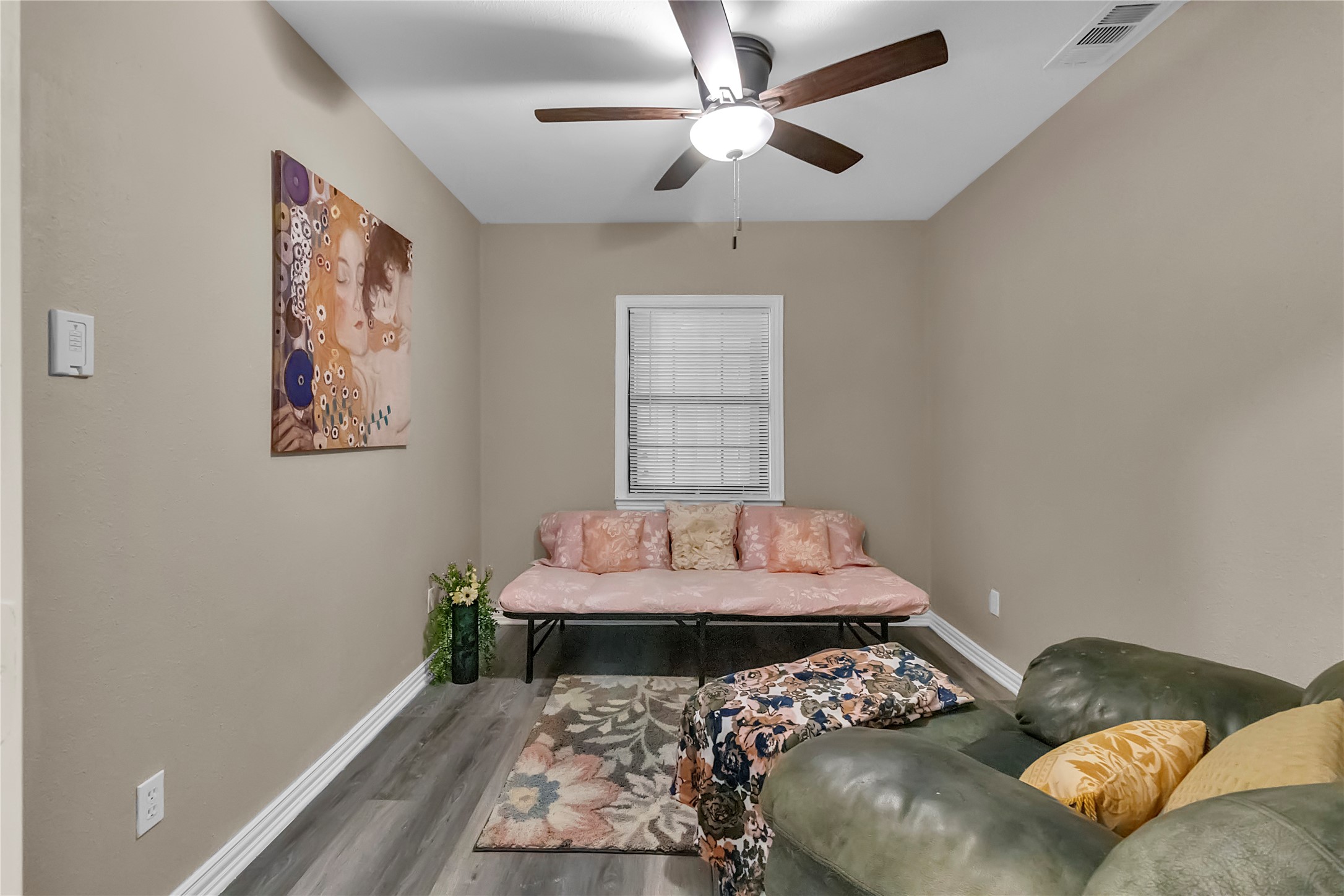 Bright and spacious 2nd bedroom with vinyl wood flooring, ceiling fan, and a window overlooking the sunroom.