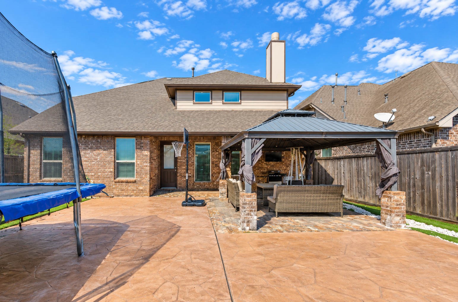 The backyard has a stamped concrete patio, a metal-roofed gazebo with a seating area and a fence that surrounds the yard. The patio is large enough for dining, lounging and entertaining, and the gazebo provides shade on sunny days. A wide open space gives room for play or a garden. This yard is ready for cookouts, birthday parties and quiet evenings outdoors. Plenty of room for family and friends to spread out.