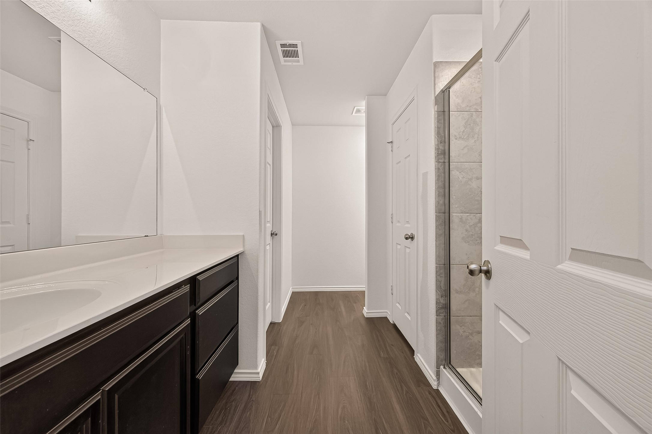 Modern primary en-suite featuring a sleek, glass-enclosed walk-in shower and an expansive vanity with ample space for everyday convenience.