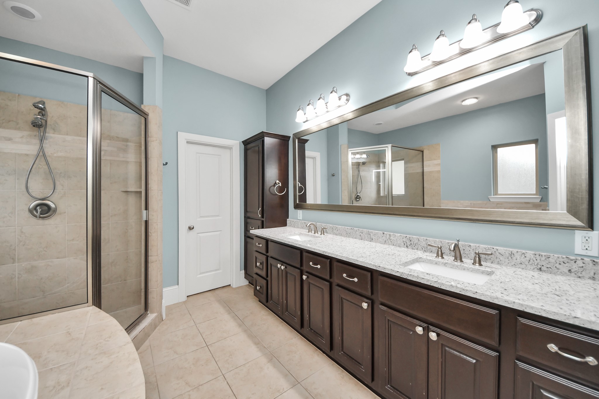 Experience luxury in the primary bathroom featuring dual sinks, a soaking tub, walk-in shower, private water closet, and convenient access to one of the two primary suite closets.