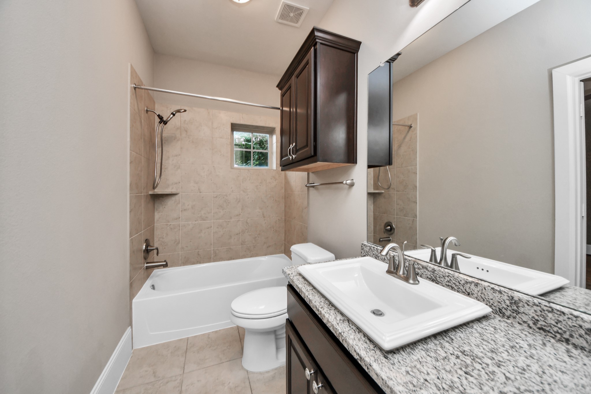 Stylish and convenient, this downstairs en-suite bathroom boasts elegant granite countertops and a shower-tub combo.