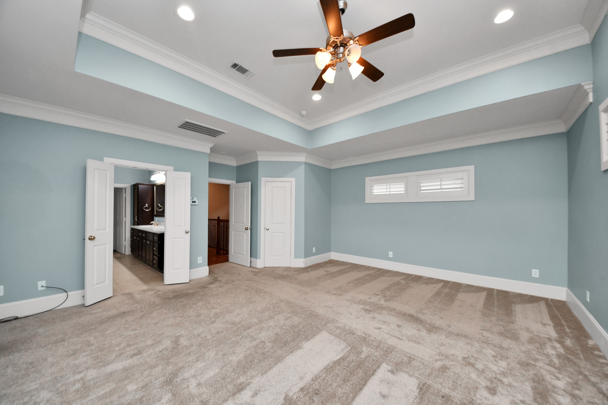 Spacious primary bedroom with elegant tray ceilings and dual closets for ample storage.