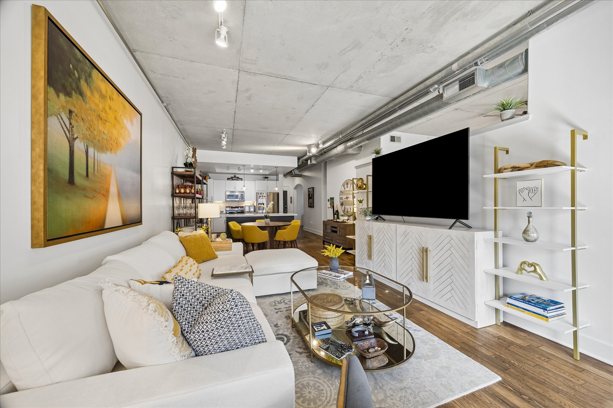 Truly open-concept all the way through.  The living room features a cozy sectional sofa, modern decor, and a sleek entertainment center, seamlessly flowing into a contemporary kitchen and dining area.