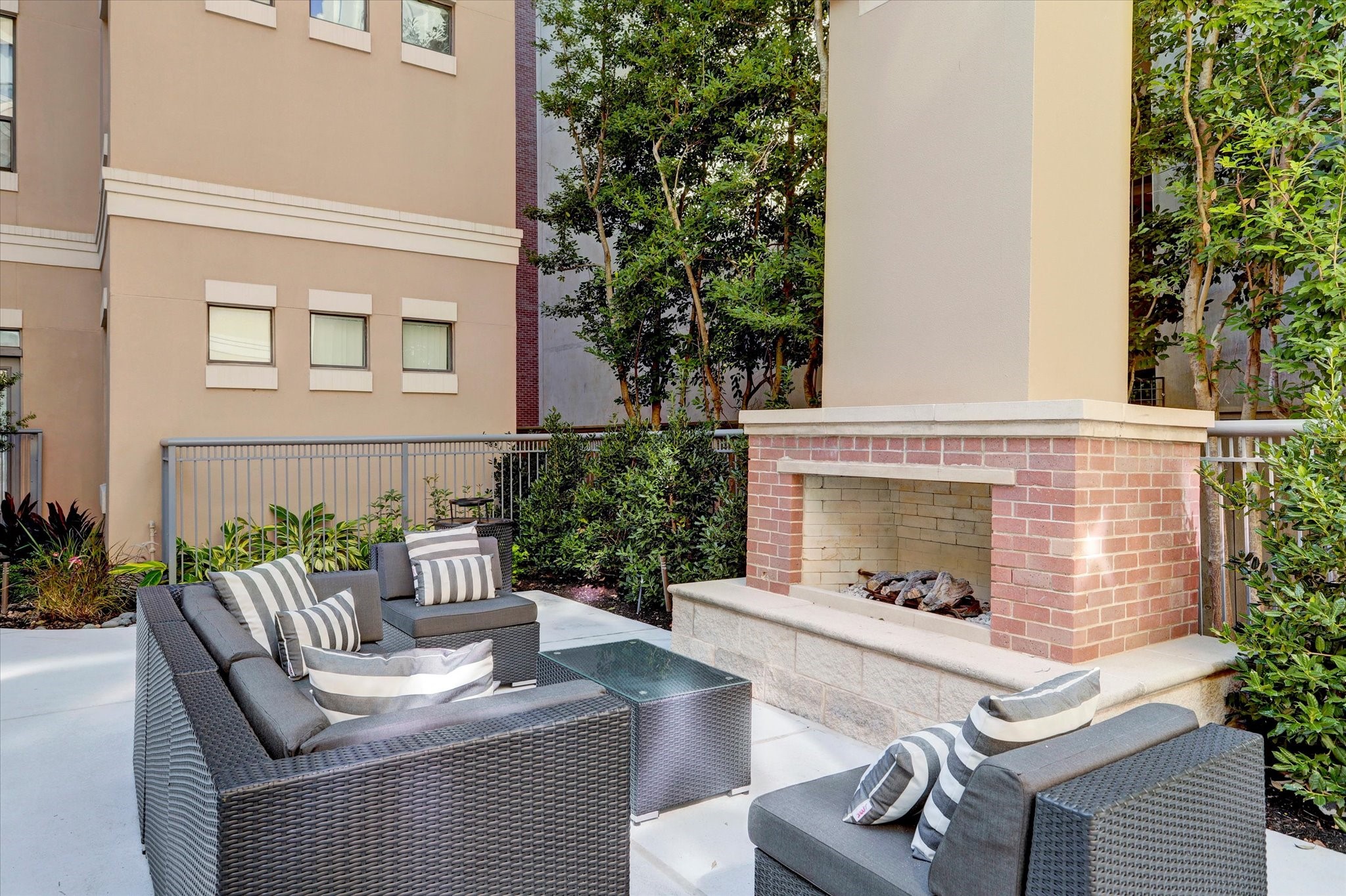 One of the many outdoor living spaces featuring a cozy brick fireplace and stylish seating, perfect for entertaining or just hanging out by the fire.