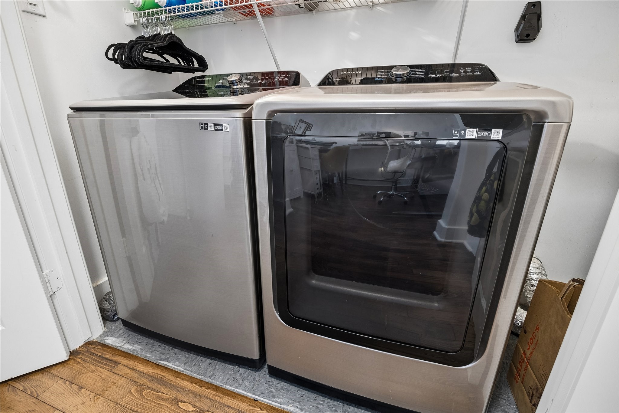 Laundry area featuring sleek, high-efficiency washer and dryer set with convenient shelving for storage.