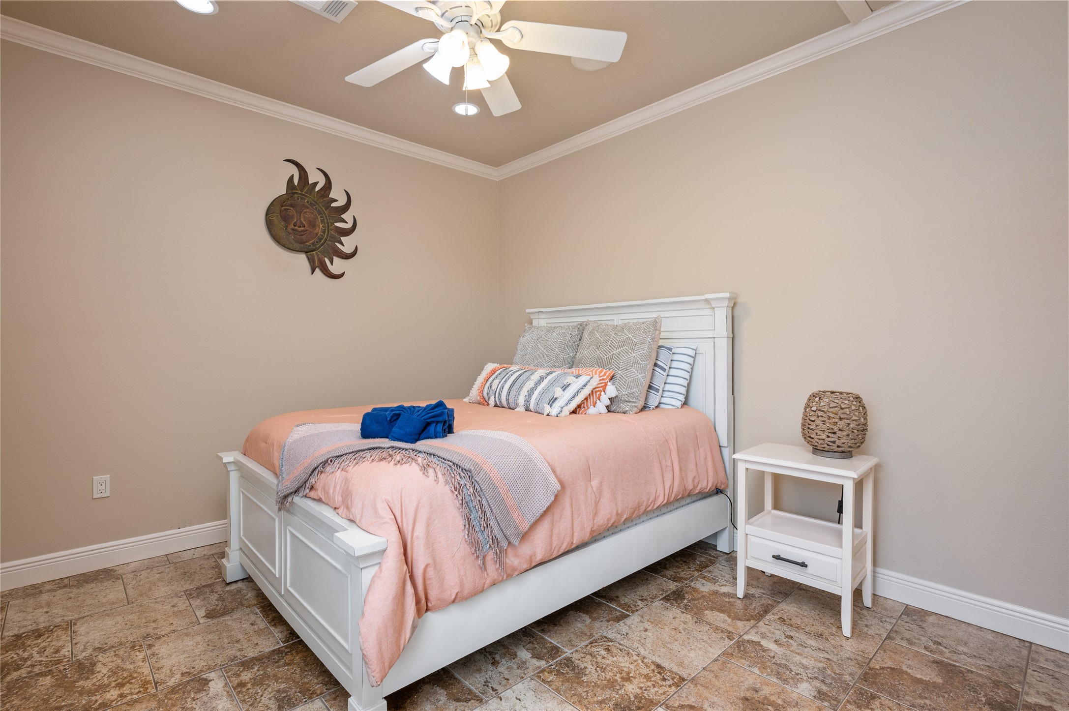 Settle into this inviting bedroom where warm coastal touches, easy-care tile flooring, and a ceiling fan create a comfortable place to recharge.