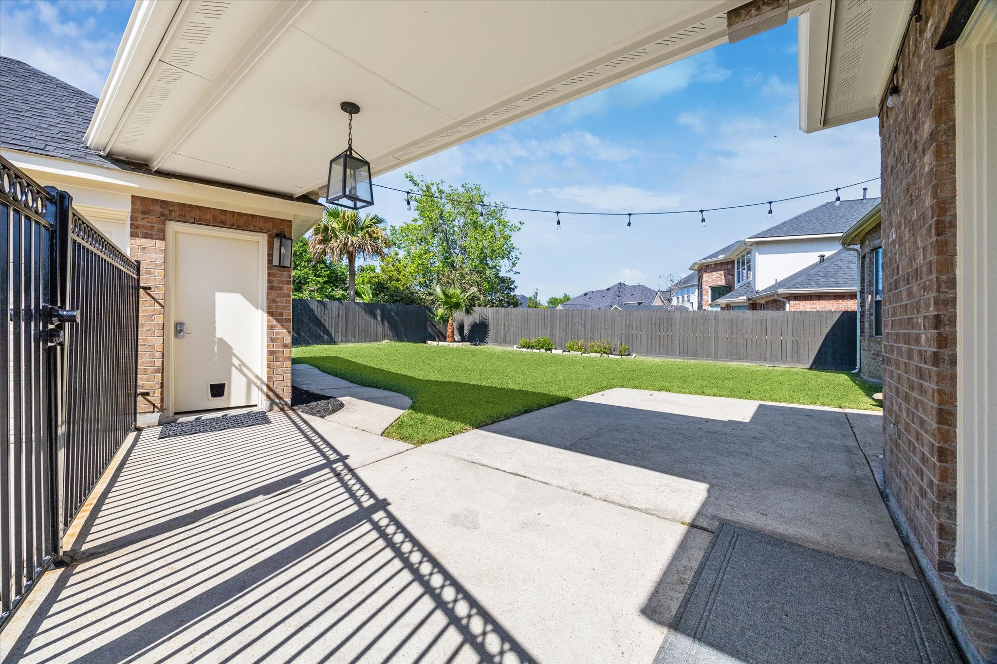 Large concrete back patio w breezeway from garage & wrought iron gate