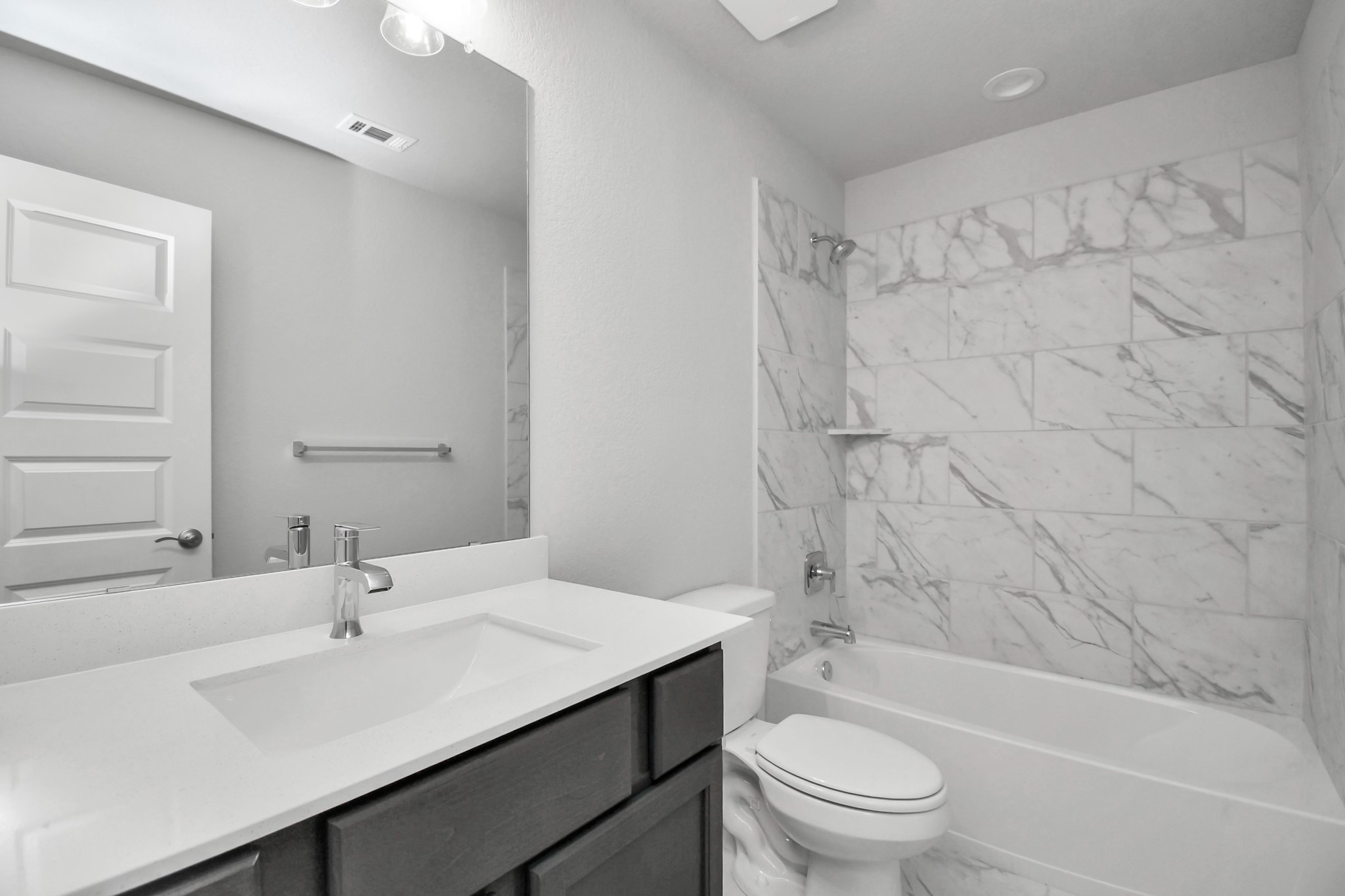 Secondary bath features tile flooring, bath/shower combo with tile surround, light stained wood cabinets, beautiful light countertop. Sample photo of completed home with similar floor plan. Actual colors and selections may vary.