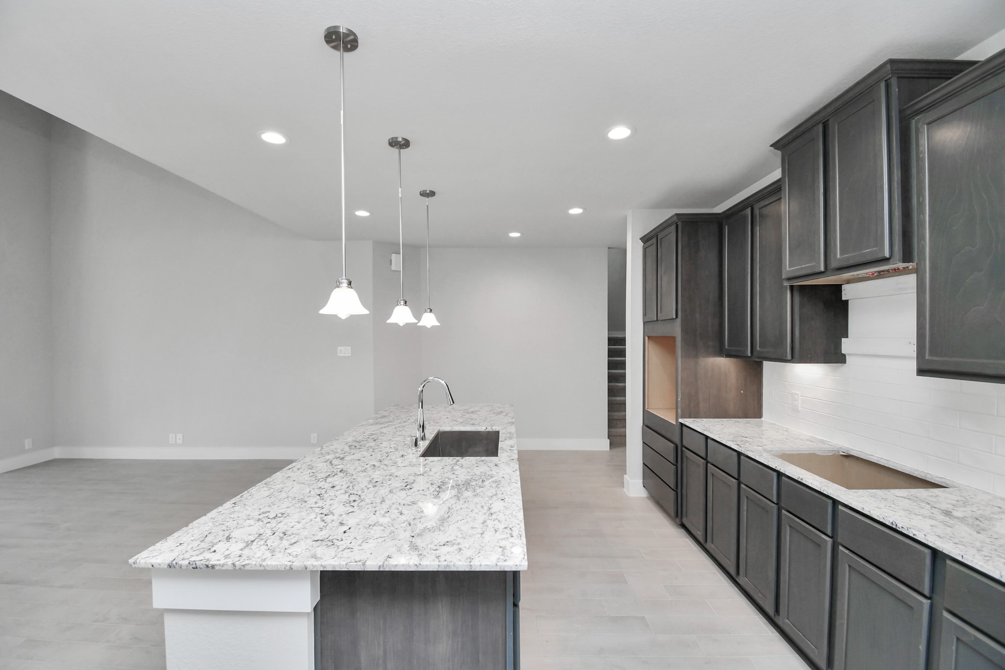 The kitchen is a culinary haven, featuring granite countertops, a tile backsplash, stainless steel appliances, 42 upper cabinets, and undercabinet lighting. Sample photo of completed home with similar floor plan. Actual colors and selections may vary.