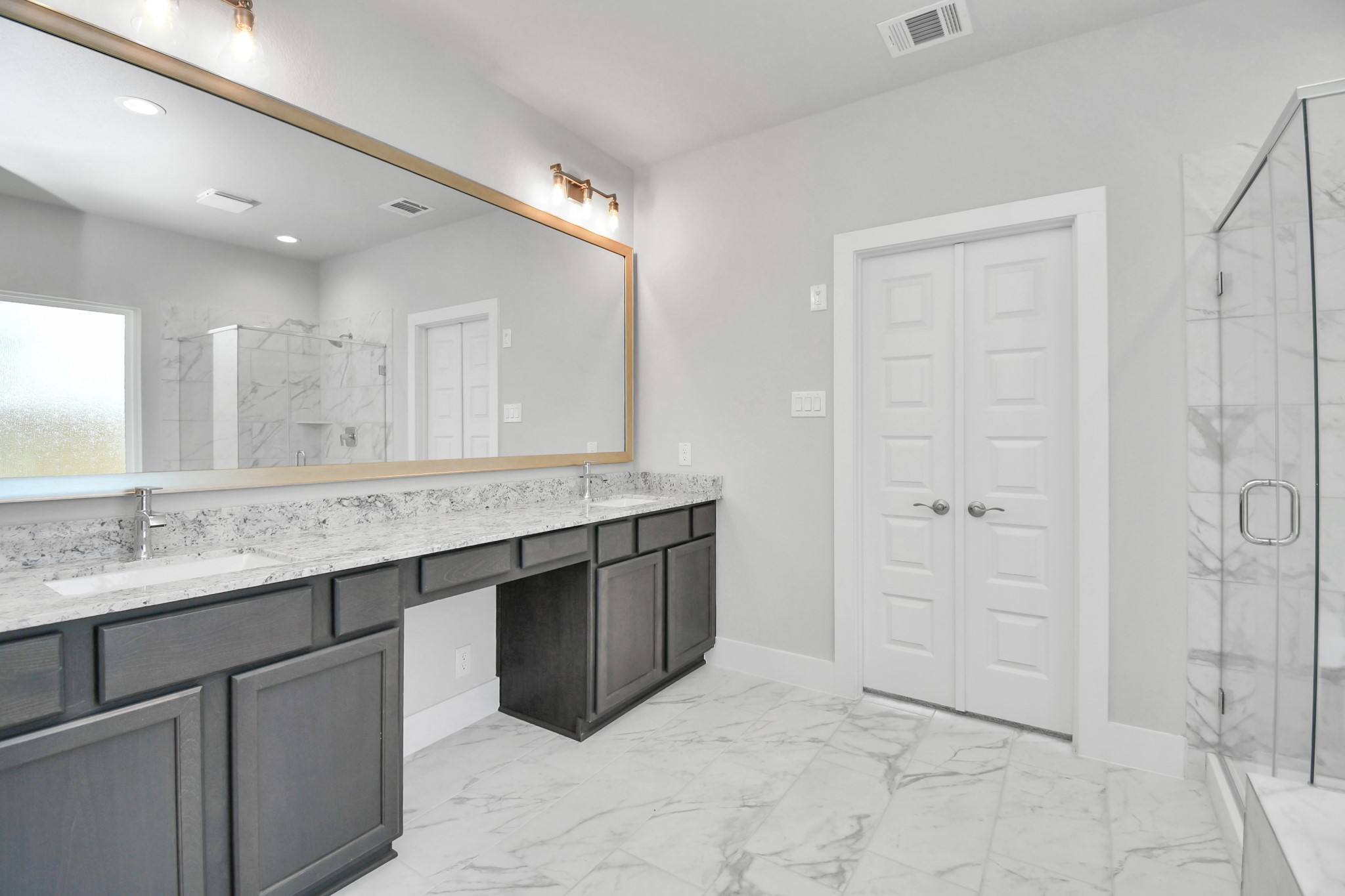 Elevate your daily routine at the elegant vanity, now equipped with double sinks, light countertops, modern hardware, and beautiful vanity lights. Sample photo of completed home with similar floor plan. Actual colors and selections may vary.