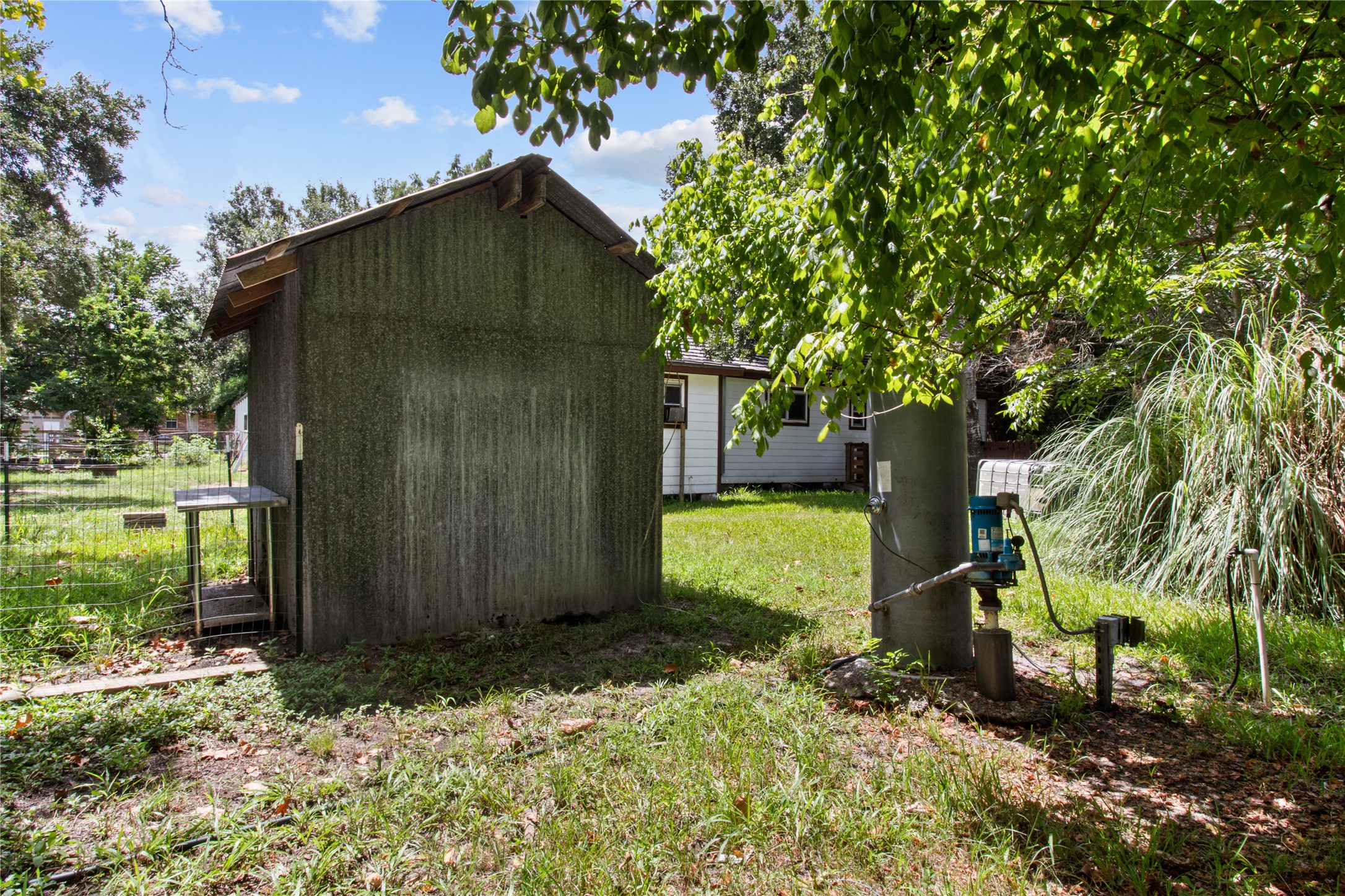 Spacious rear of property features a utility shed, mature trees, and a well pump that feeds the back side of the property. Imagine the many options for this functional outdoor space.