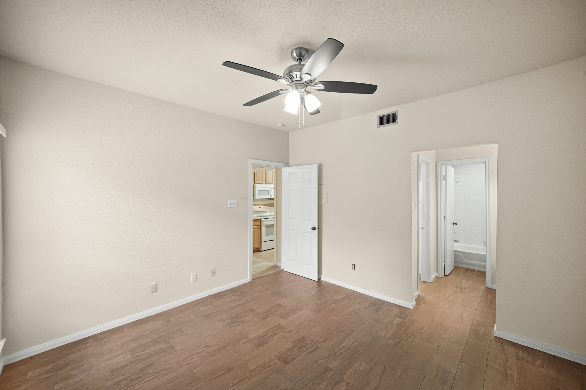 A bright bedroom featuring wood like flooring and a modern ceiling fan for comfort.
